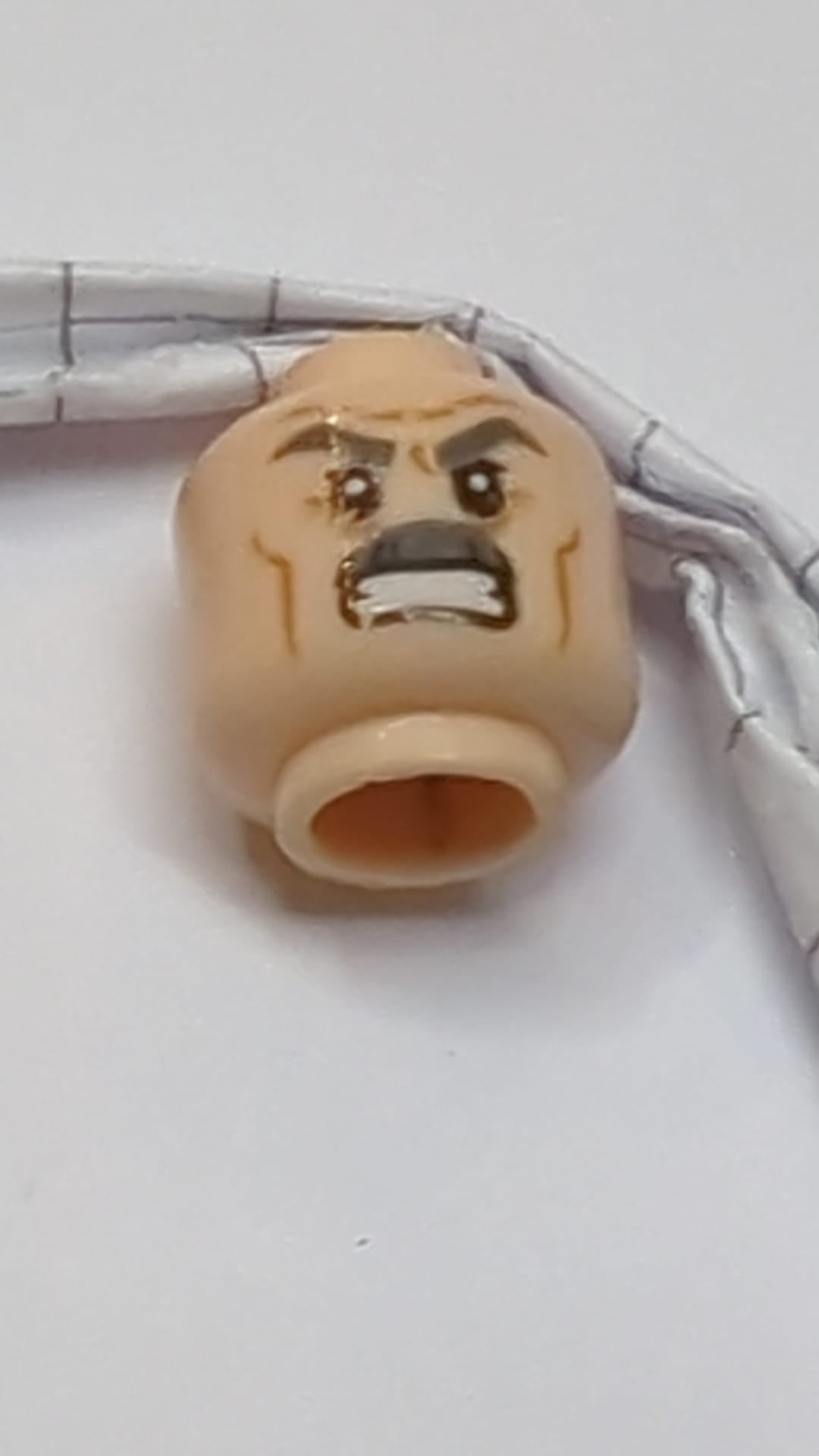 Minifigur, Kopf doppelseitig, dunkelblaugrau, dichte Augenbrauen und Schnurrbart, mittelbraune Wangenfalten, Stirnrunzeln, neutraler Gesichtsausdruck und Grübchen am Kinn / wütender Gesichtsausdruck mit entblößten Zähnen hellnougat (fleischfarben)