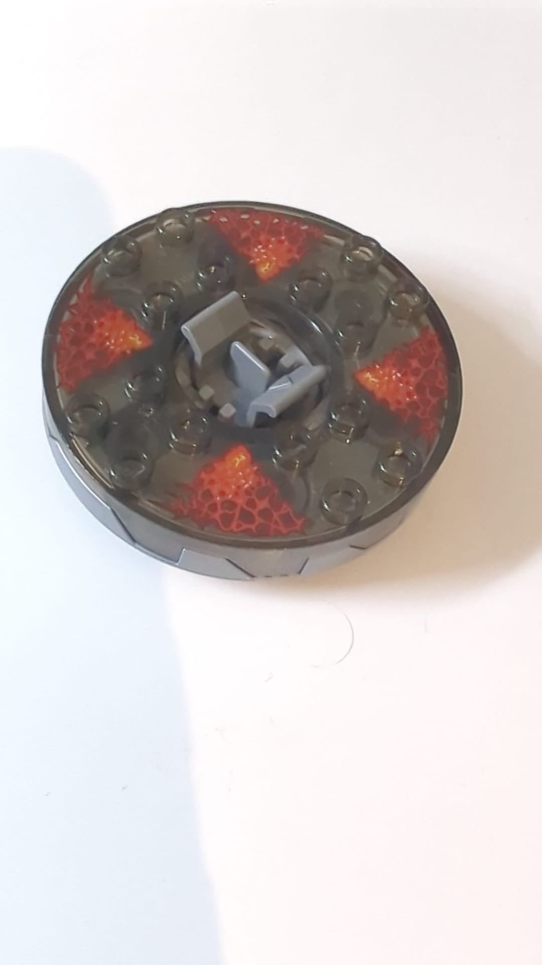 6x6x1 1/3 Ninjago Spinner, runde Basis mit Zahnung, Oberseite transparent-braun mit rotem Energiemuster pearlsilber