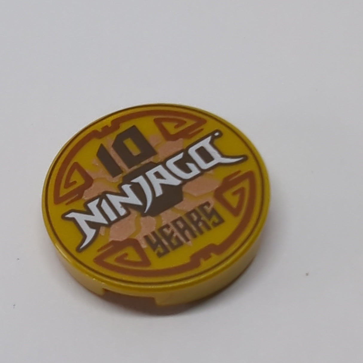 NEU Tile, Round 2 x 2 with Bottom Stud Holder with '10 NINJAGO YEARS' Pattern pearlgold pearl gold