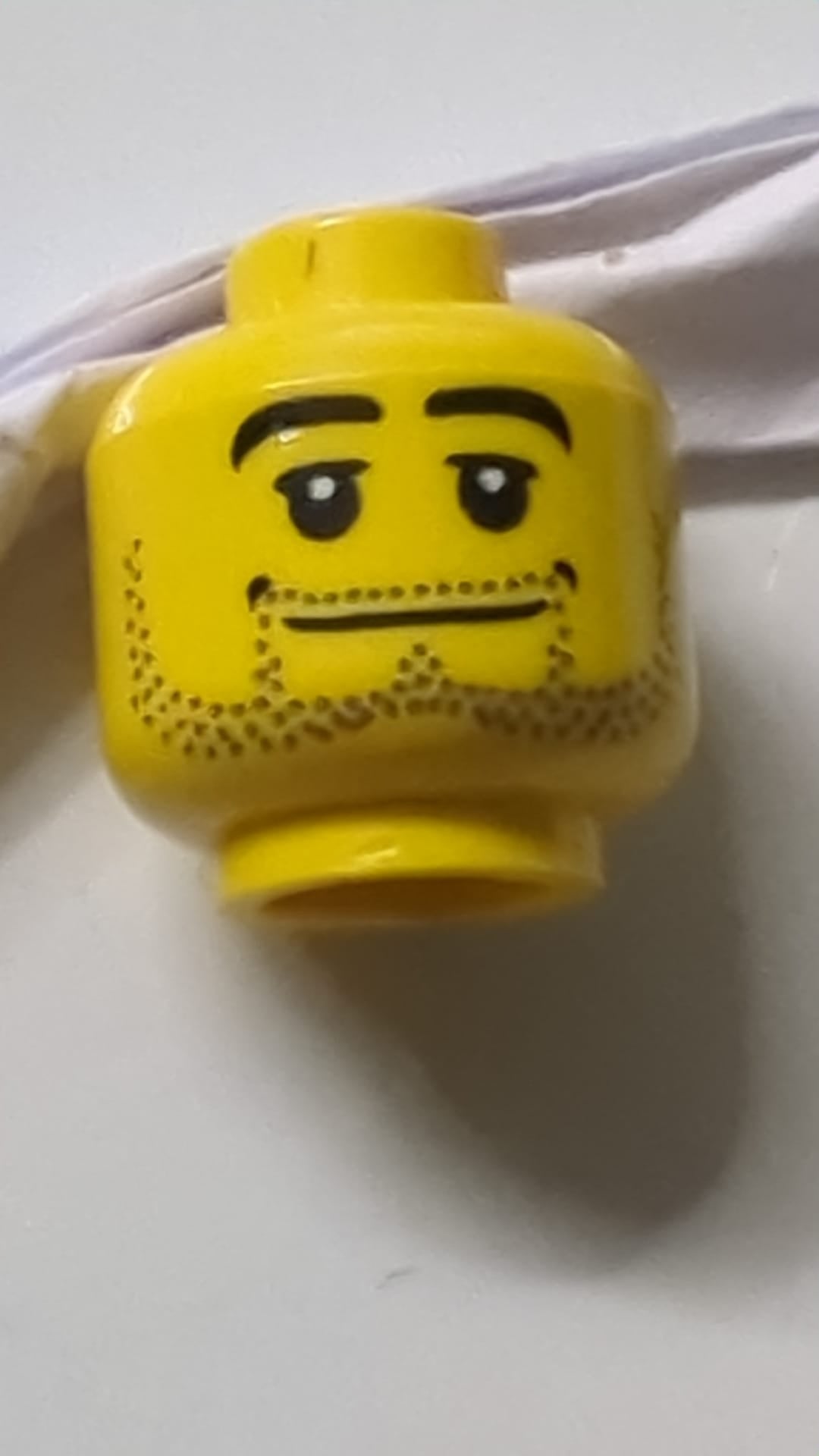 Minifigur, Kopf, Bartstoppeln, schwarze Augenbrauen, breiter Mund, weiße Pupillen gelb