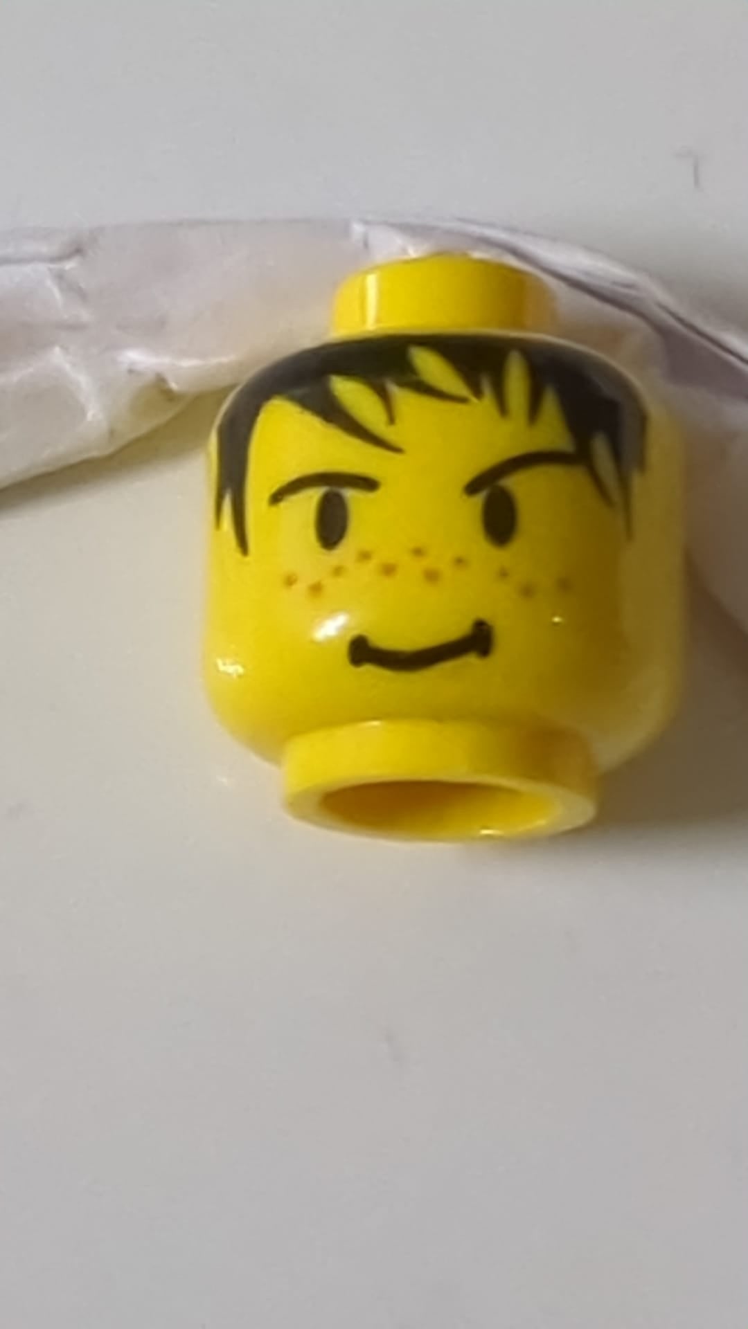 Minifigur, männlicher Kopf mit stacheligen schwarzen Haaren, Sommersprossen und einem Grinsen auf der Nase gelb