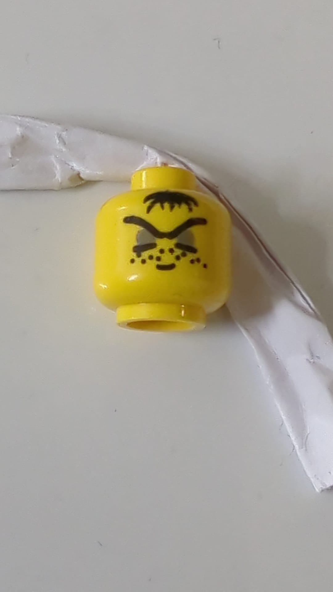 Minifigur, schwarzer Haarbüschel, geschlossene Augen, dunkelgraue Augenlider, Sommersprossen, Stoppelbart gelb