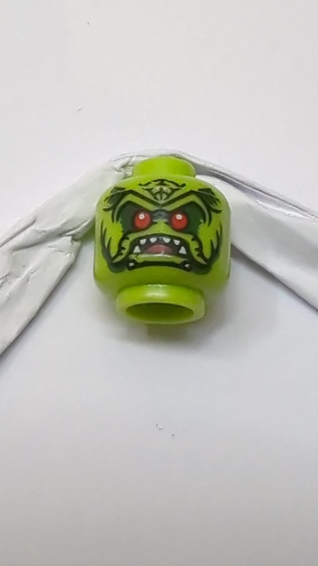 Minifigur, Alienkopf mit roten Augen, dunkelgrünem Lidschatten, schwarzen Markierungen und offenem Mund mit Zunge und scharfen weißen Zähnen lindgrün