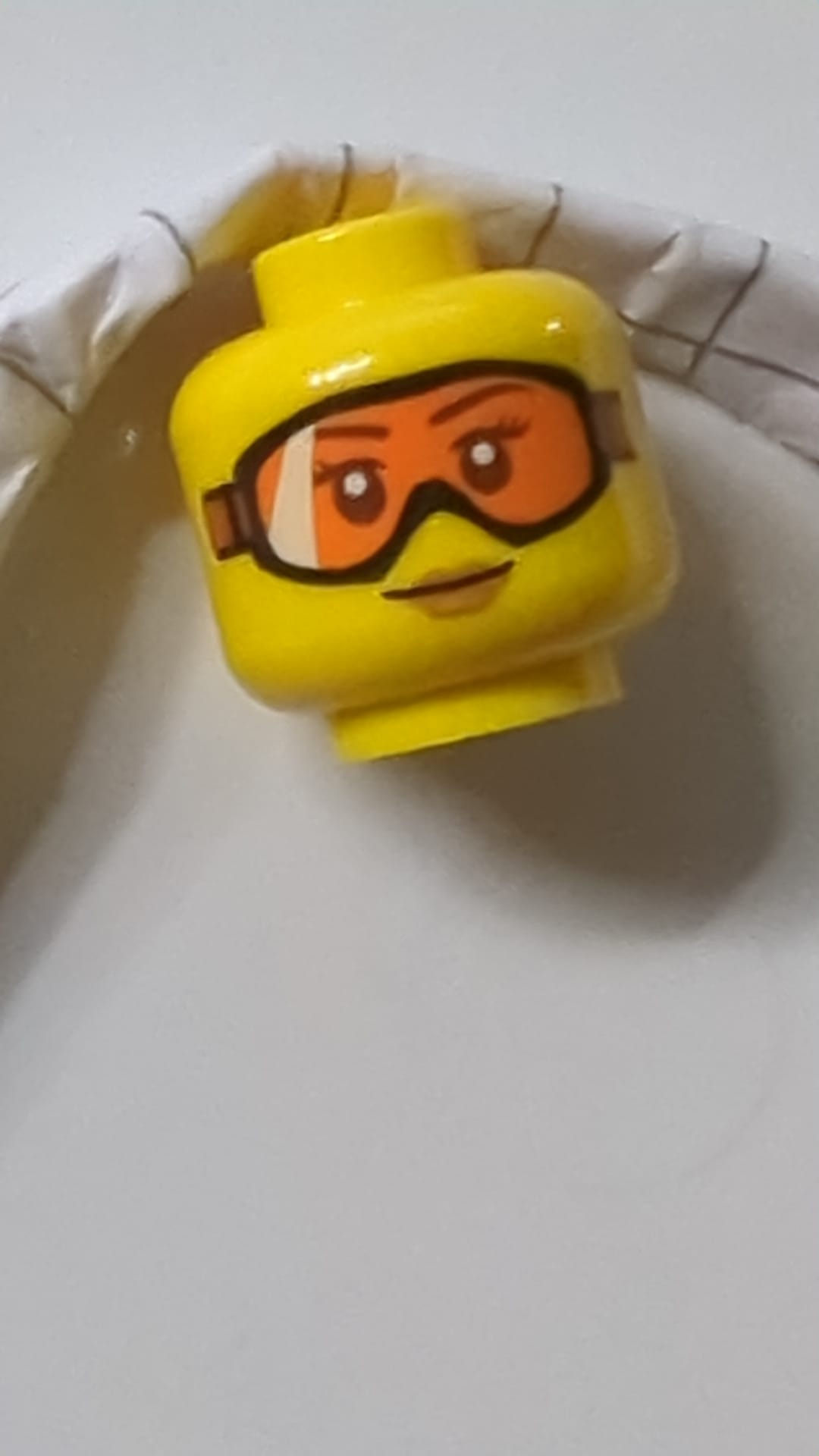 Minifigur, weiblicher Kopf mit Brille (orangefarbene Schutzbrille), mittelbraune Lippen, kleines Lächeln gelb