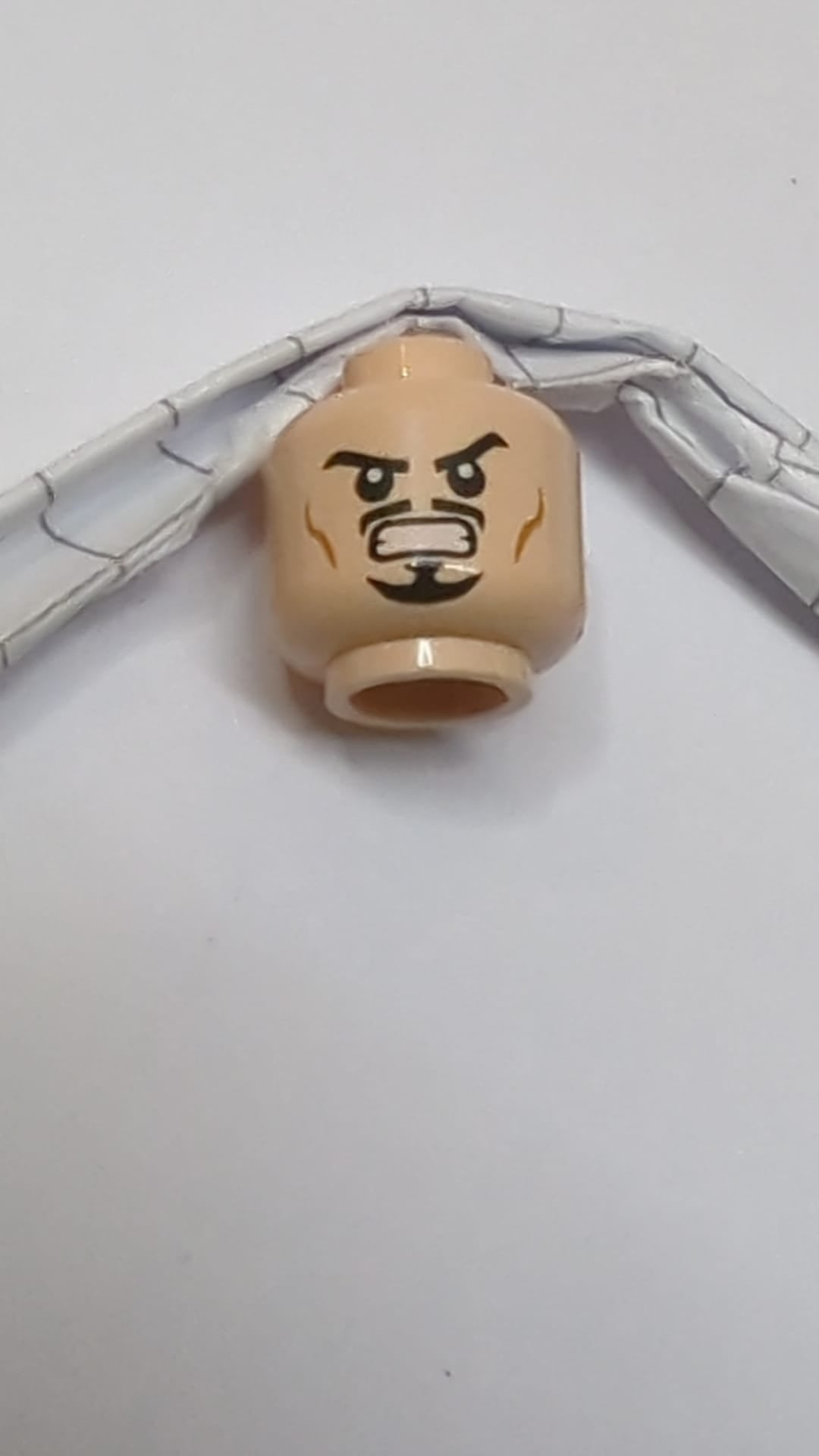 Minifigur, Kopf mit doppelseitigen schwarzen Augenbrauen, gestutztem Schnurrbart und Spitzbart, mittelhohen Wangenfalten, entschlossenem Grinsen / wütendem Zähnefletschen hellnougat (fleischfarben)