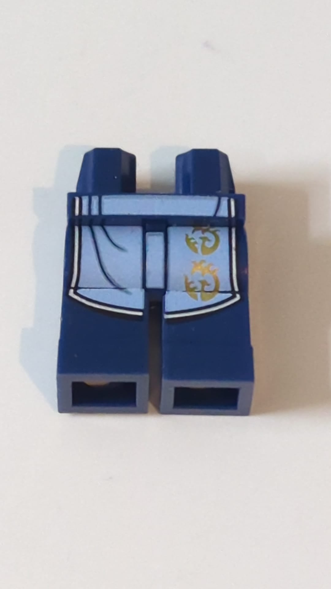 NEU Hüften und Beine mit hellblauem Gewand, das mit einem weißen Saum und einem goldenen Phönix-Symbolmuster "BAM" endet dunkelblau