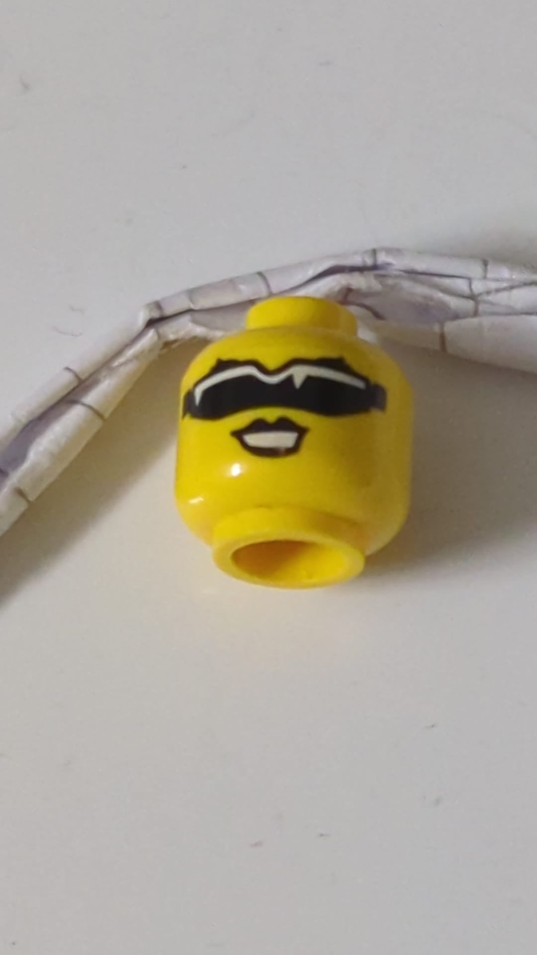 Minifigur, weiblicher Kopf mit schwarzen Augenbrauen und Lippen, Sonnenbrille mit einfacher Linse und weißen Spiegelungen, offenem Mund und Lächeln mit Zahnmuster gelb