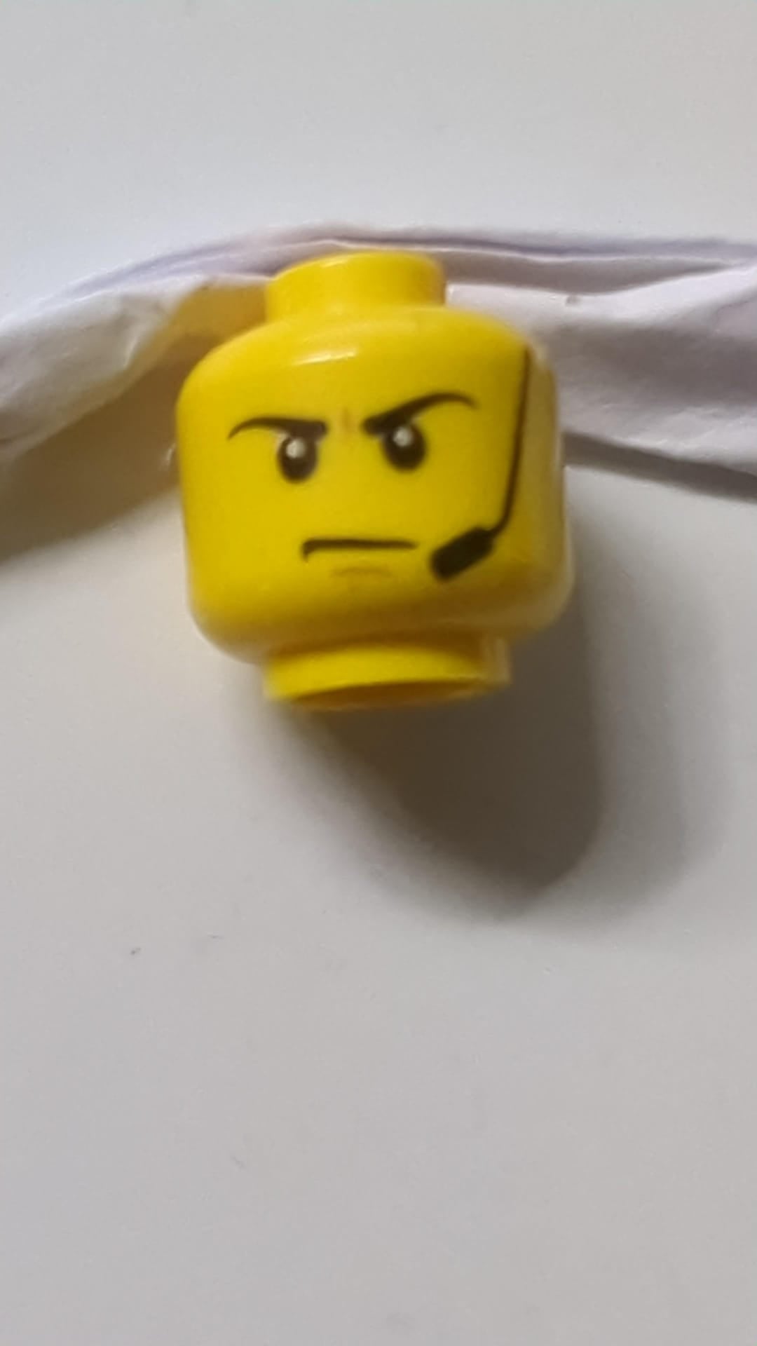 Minifigur, Kopf mit schwarzen Augenbrauen und Headset, mittelgroßes nougatfarbenes Kinngrübchen, gerunzelte Stirn, wütendes Stirnrunzeln gelb