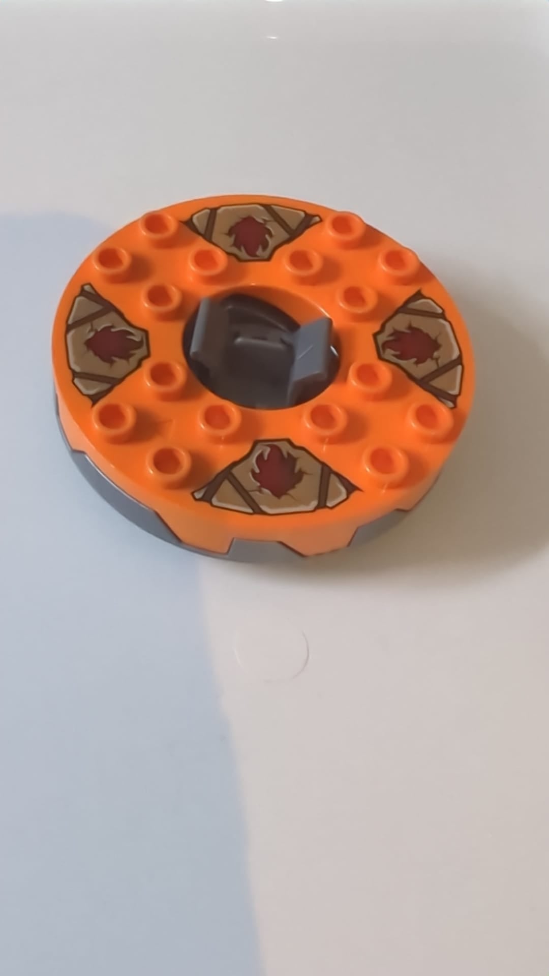 6x6x1 1/3 Ninjago Spinner, runde Basis, gezahnt, mit orangefarbener Oberseite und dunkelroten Flächen auf einem Muster in Dark Tan und Dunkelgrau pearlsilber