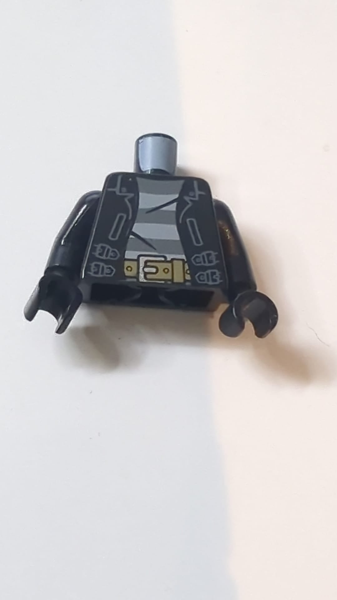 Offene Lederjacke mit Riemen über einem Hemd mit dunkelblaugrauen und hellblaugrauen Streifen, dunkelbrauner Gürtel mit silberner Schnalle / Schwarze Ärmel / Schwarze Hände schwart
