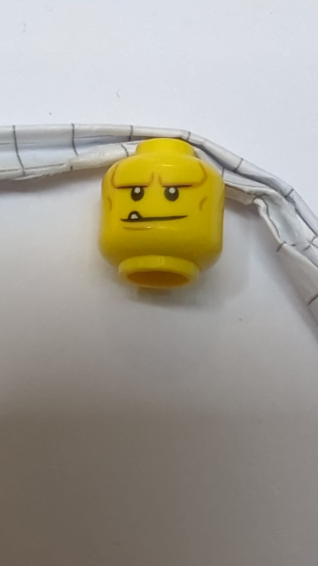 Minifigur, Kopf mit doppelseitigen schwarzen Augenbrauen, weißen Pupillen, Grübchen am Kinn und Wangenfalten, Lächeln mit Zähnen / Stirnrunzeln mit wütendem Gesichtsausdruck gelb