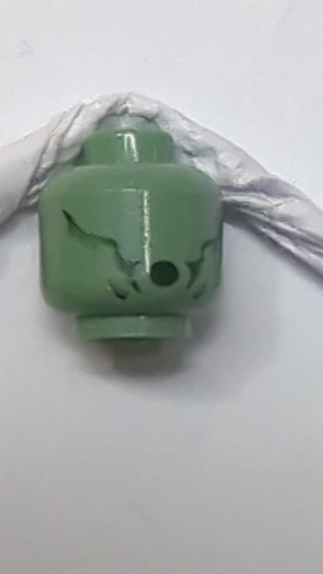 Minifigur, Kopf eines Alien-Dementors mit schwarzen, verblassten Wangenlinien, ovalem, offenem Mundmuster sandgrün