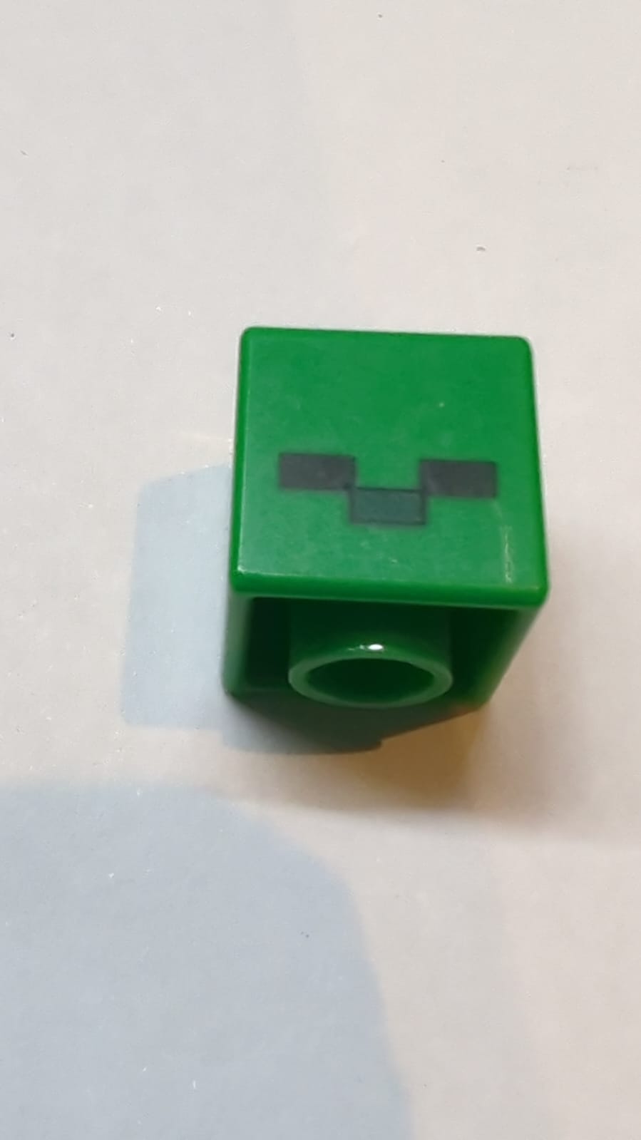 Kopf, modifizierter Würfel mit pixeligen schwarzen Augen und dunkelgrünem Nasenmuster (Minecraft-Zombie)