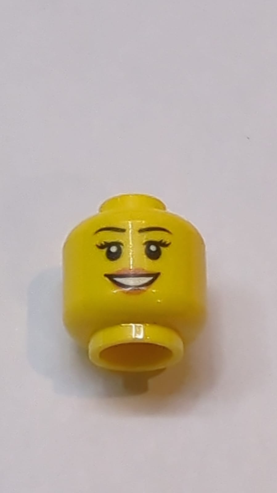 Kopf einer Frau mit schwarzen Augenbrauen und Wimpern, dunkelorangefarbenen Lippen, offenem Mundlächeln mit Zahnmuster