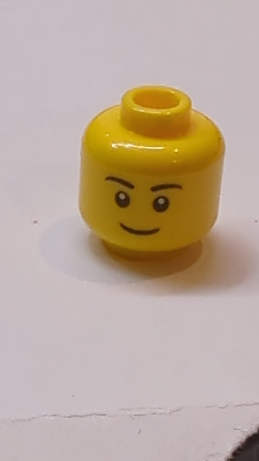 Kopf mit schwarzen Augenbrauen, schmales Grinsen, schwarze Augen mit weißer Pupillenmuster