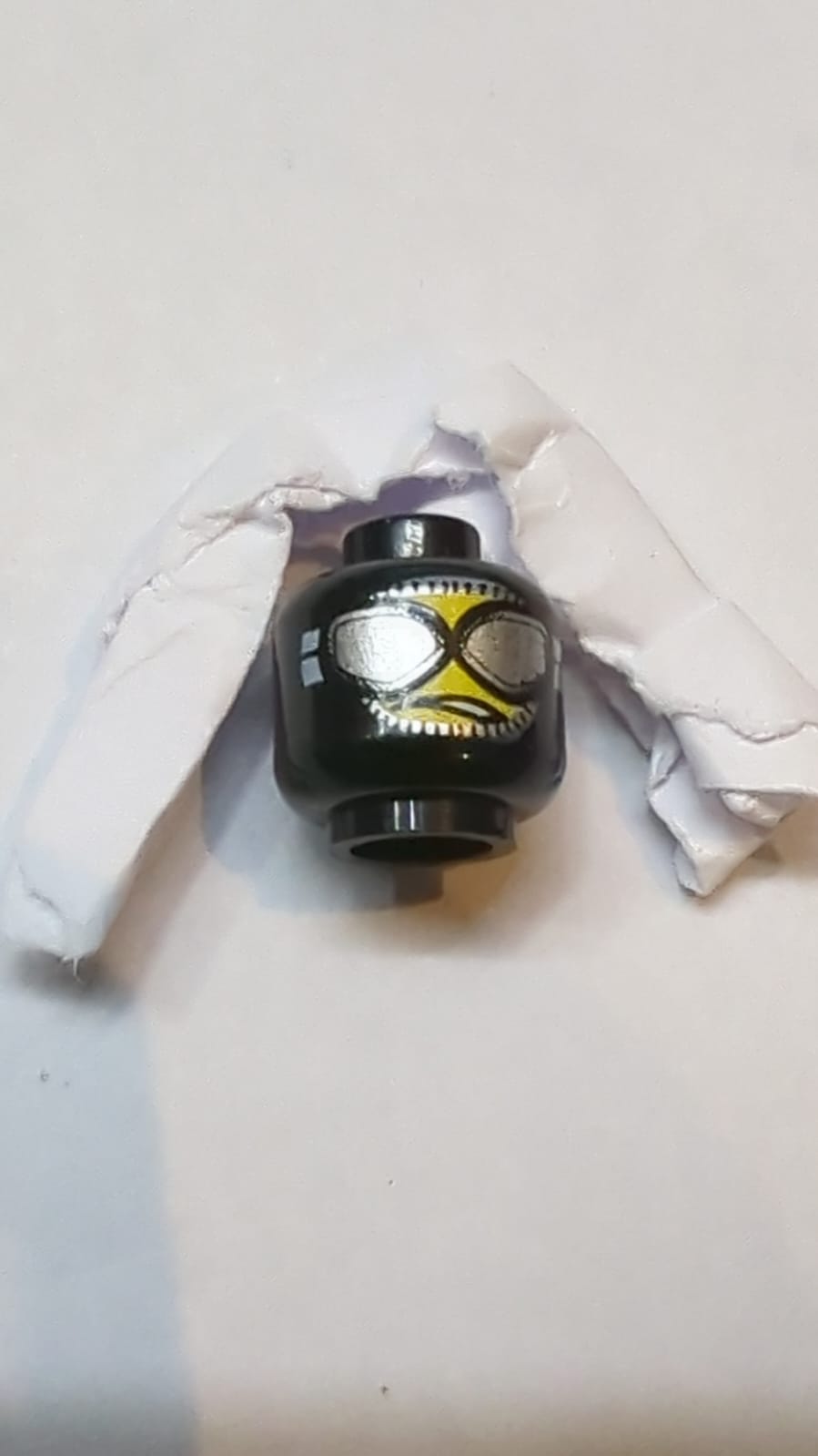 Kopf-Balaclava mit gelbem Gesicht, silberne Schutzbrille mit weißem Riemen, schiefes, offenes Mundgrimassen mit Zahn-Muster