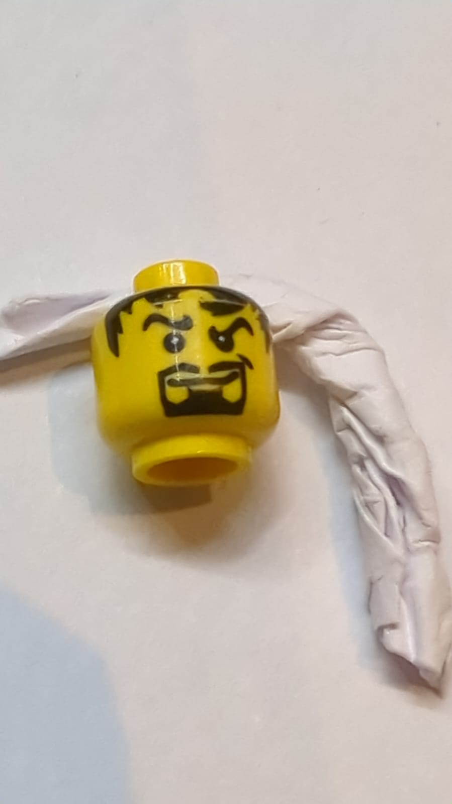 Kopf Schwarze gewellte Augenbrauen, unordentliches Haar, dünner Schnurrbart, Spitzbart, schiefes Grinsen mit Grübchenmuster