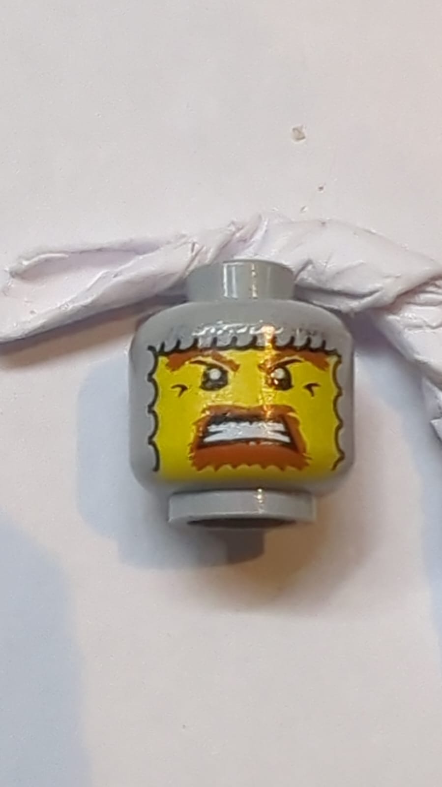 Kopf Sturmhaube mit silbernem Kettenhemd, gelbem Gesicht, dunkelorangenen Augenbrauen und Kinnbart, wütend mit gebleichten Zähnen Muster