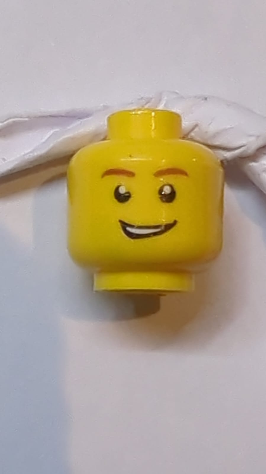 Kopf Männliche rötlich-braune Augenbrauen, offenes schiefes Grinsen mit Zähnen, weiße Pupillenmuster