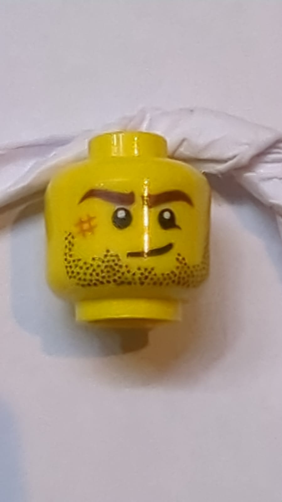 Kopf Dunkelbraune Augenbrauen, schwarzer Bartstoppel, dunkelorangefarbener Kratzer, schiefes Grinsenmuster