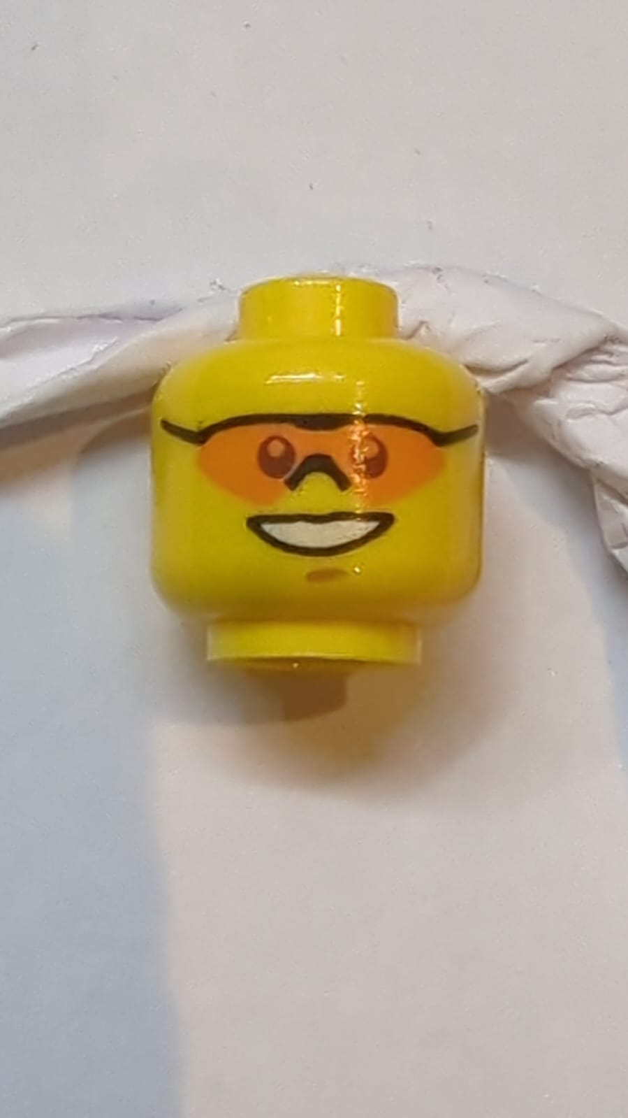 Kopf Sonnenbrille mit einzelner orangefarbener Linse und schwarzem Nasenstück, mittlere nougatfarbene Kinngrube, offenes Lächeln mit Zahnaufdruck