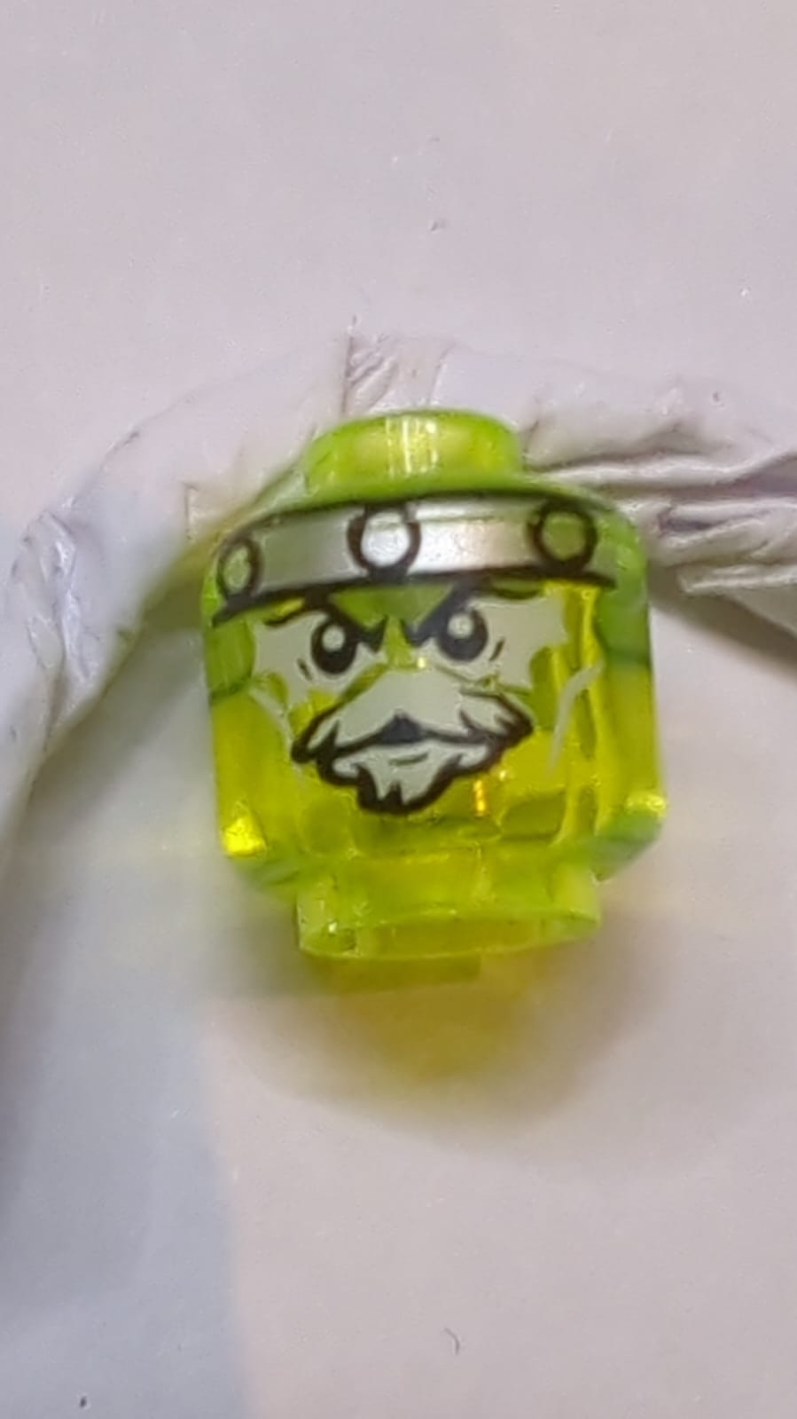 Kopf Außerirdischer Geist mit grauem Kinnbart, gelblich-grünen Augen und Metallband auf Vorder- und Rückseite des Musters