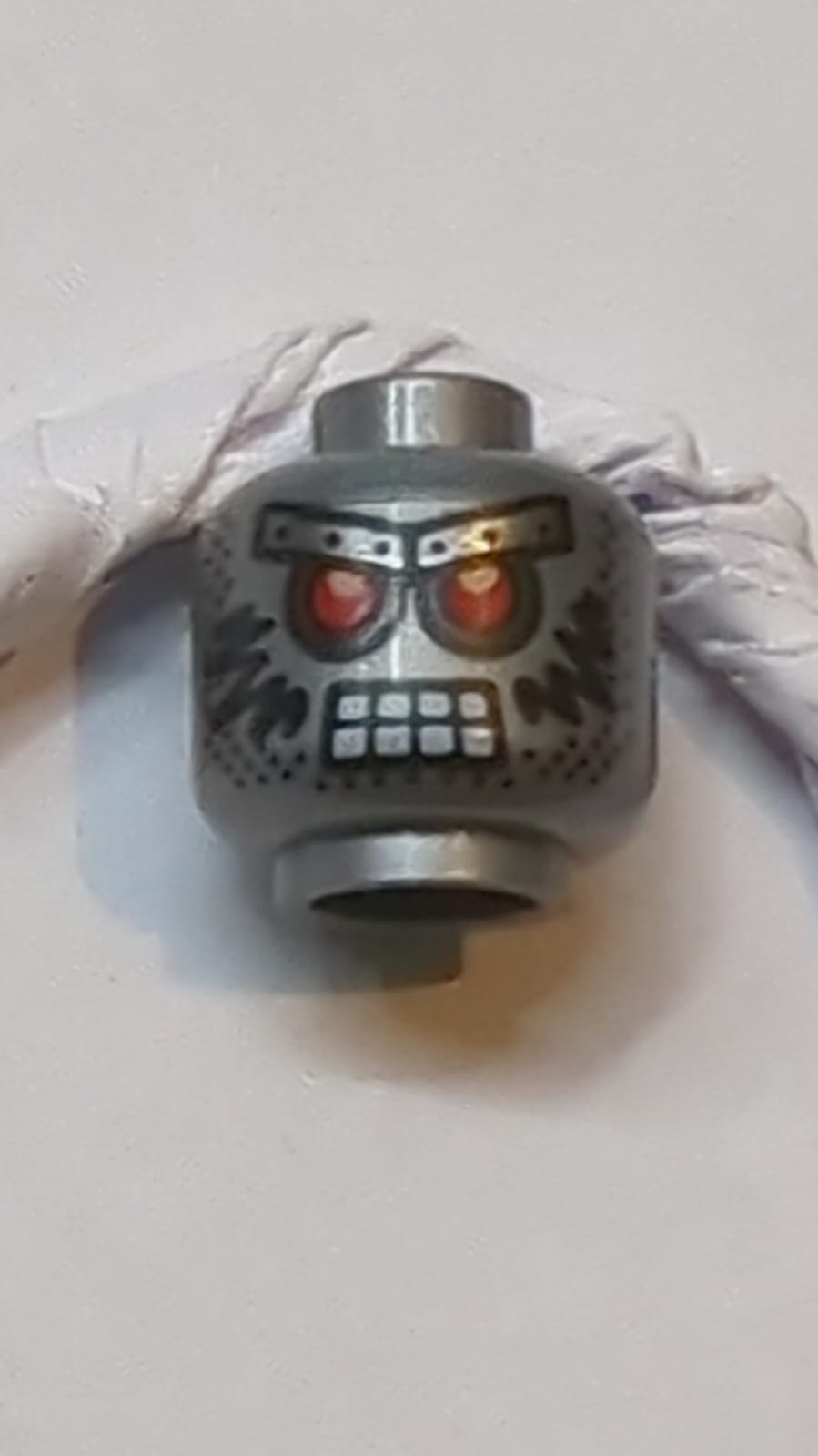 Kopf Außerirdischer mit roten Augen, metallischen Augenbrauen mit Nieten, 8 Mundquadraten, Stoppelbart und schwarzem Muster