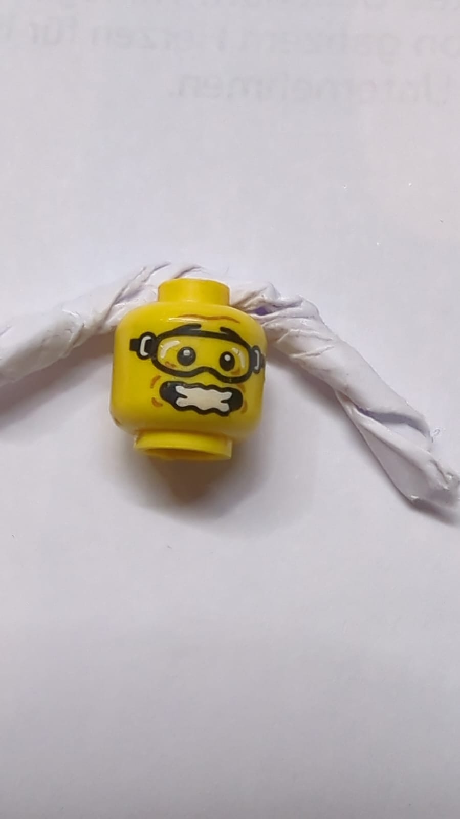 Kopf, schwarze Augenbrauen, Schutzbrille, mittlere Nougat-Grübchen, zusammengezogene Stirn, offener Mund erschrocken und wellig mit Zahnmuster gelb