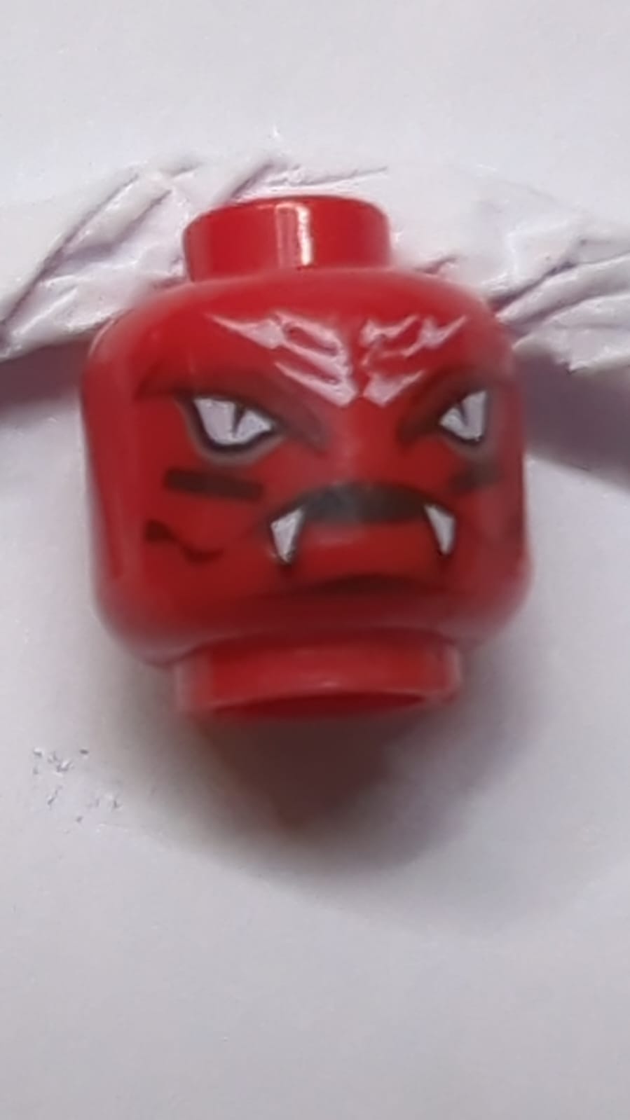 Kopf-Außerirdischer mit weißen Schlangenaugen und Stirnschuppen, schwarzen Linien auf den Wangen, weit geöffnetem Mund mit Fangzahnmuster rot