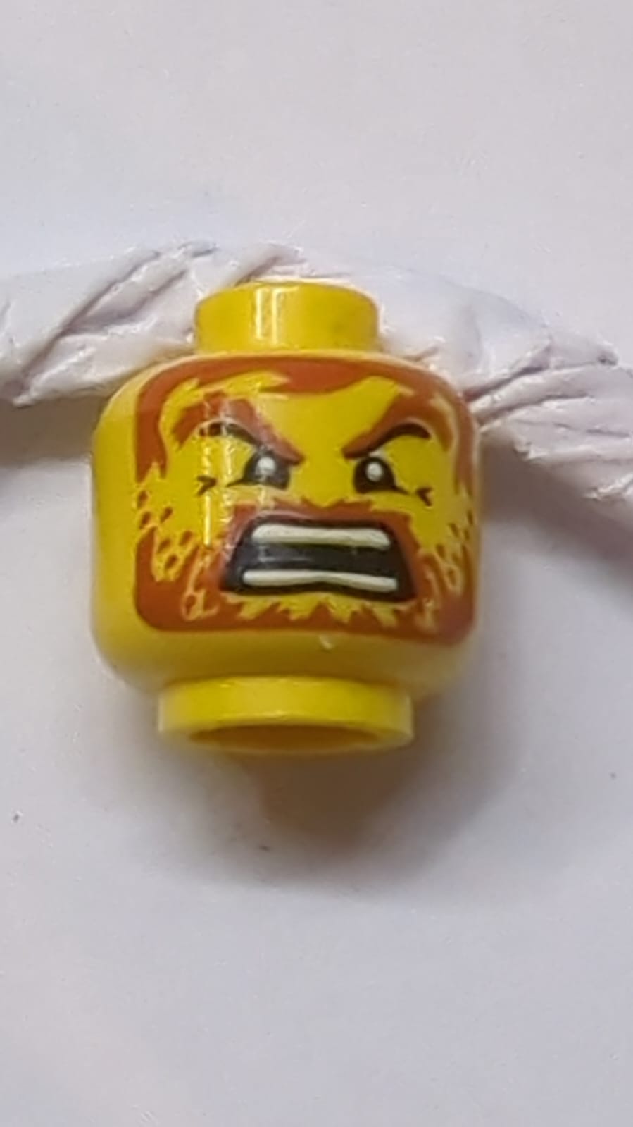 Kopf dunkelorange, Augenbrauen, Schnurrbart, Vollbart mit Stoppel und Haare, wütender offener Mund mit auseinanderstehenden Zähnen gelb