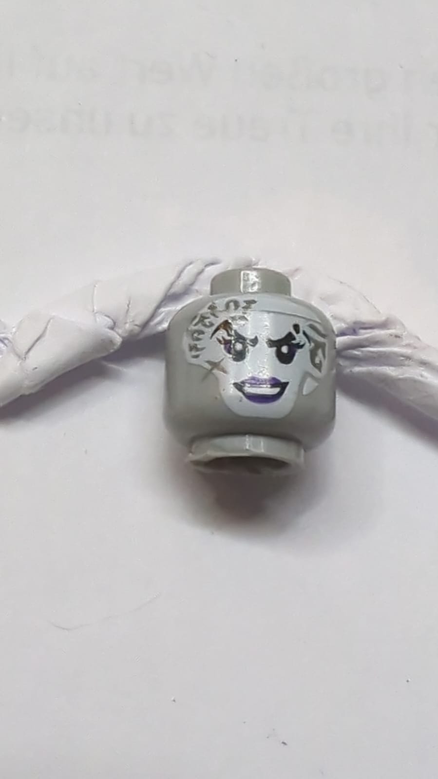 Kopf einer weißen Frau mit dunklen bläulich-grauen Tätowierungen im Gesicht, dunklem lila Lidschatten und Lippenmuster neuhellgrau