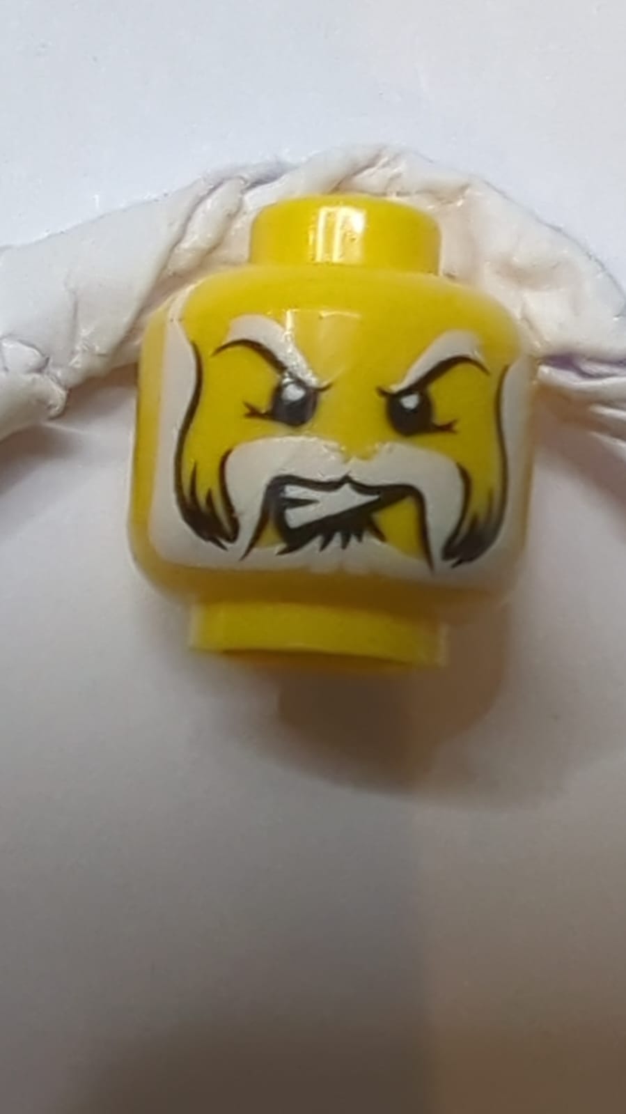 Kopf Schwarz mit weißen Augenbrauen, Schnurrbart und Vollbart, schiefe wütende Zähne-Muster gelb