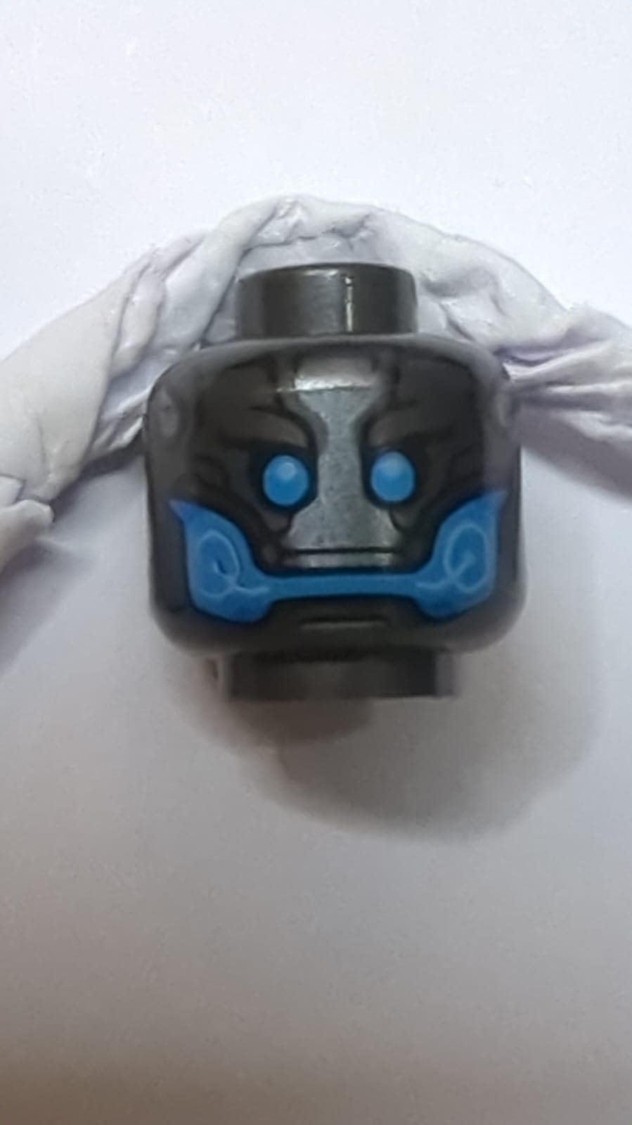 Kopf eines Aliens mit blauen Augen und Mund und Silberplattenmuster titan