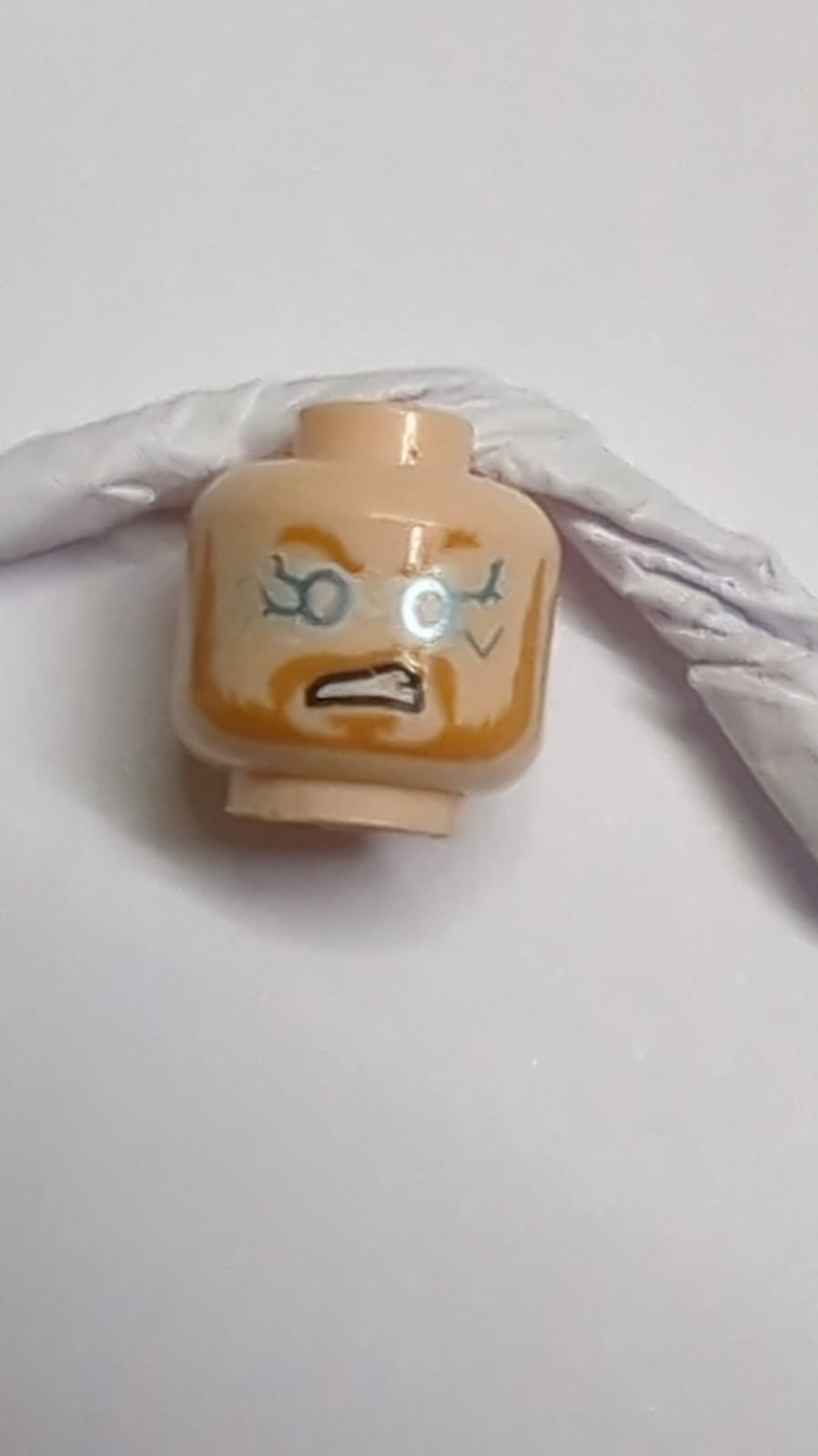 Minifigur, Kopf doppelseitig, mittleres Nougat, Augenbrauen, Schnurrbart und Bart, neutral / metallisches Hellblau und weiße Blitzaugen und wütender offener Mund mit Zähnemuster nougat (hell)