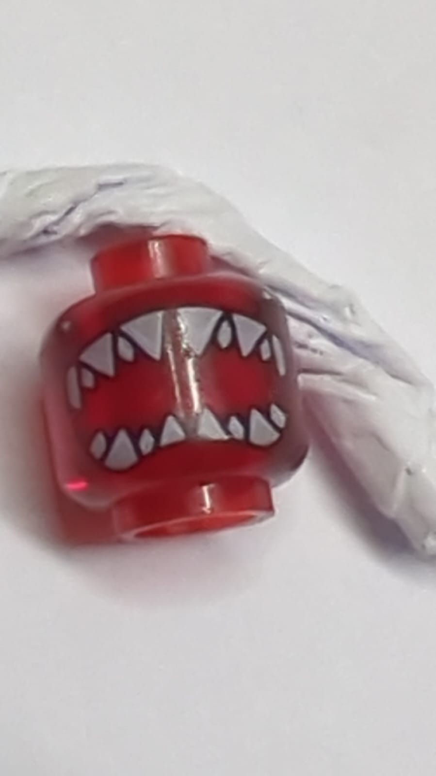 Minifigur, Kopf eines Aliens mit schwarzen Augen, großer offener Haifischmund mit scharfen Zähnen, geteiltes Muster transparent rot