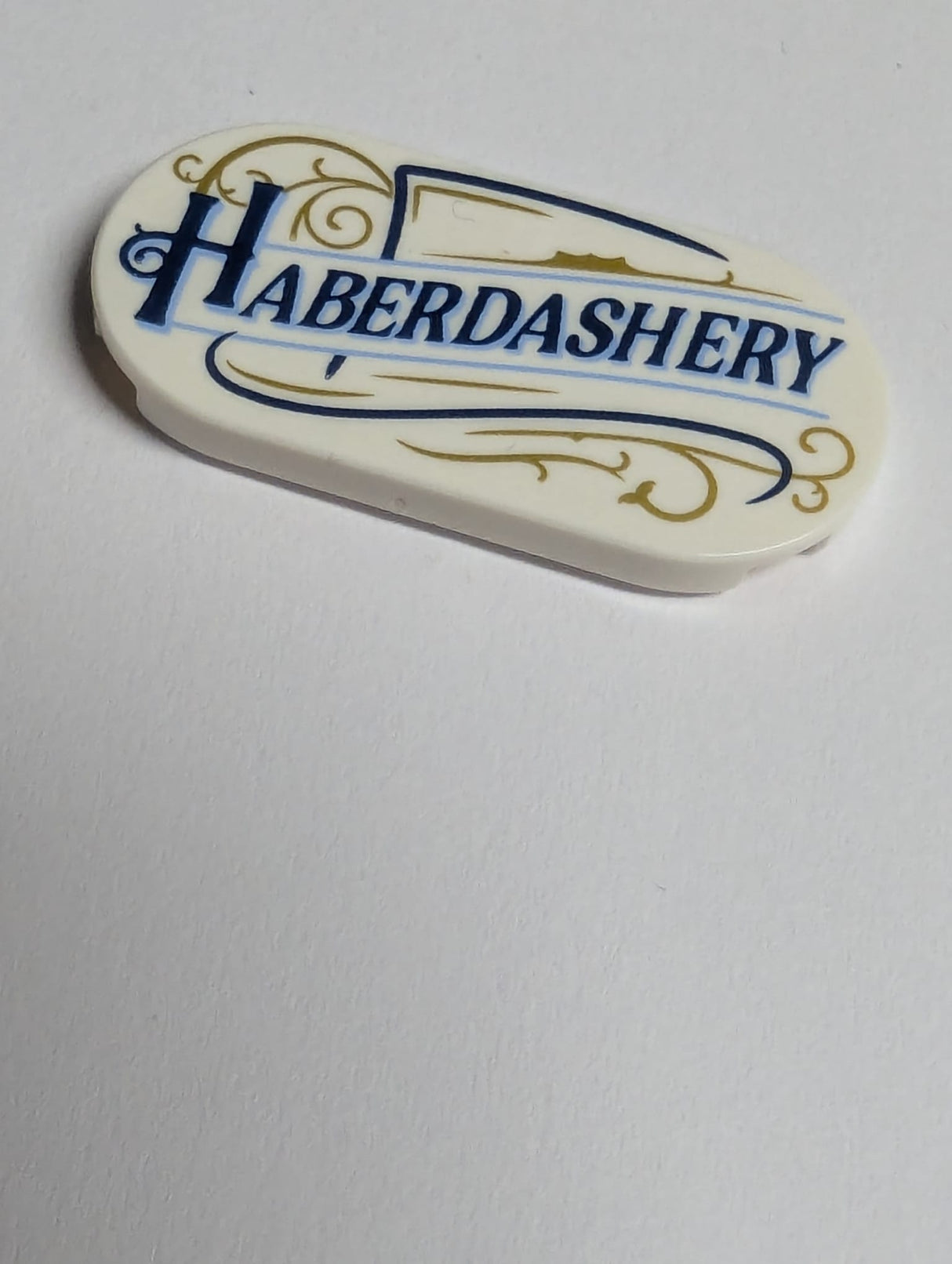 NEU Fliese, rund 2 x 4 oval mit dunkelblauem und mittlerem blauem 'HABERDASHERY' und goldenem Rankenmuster weiß