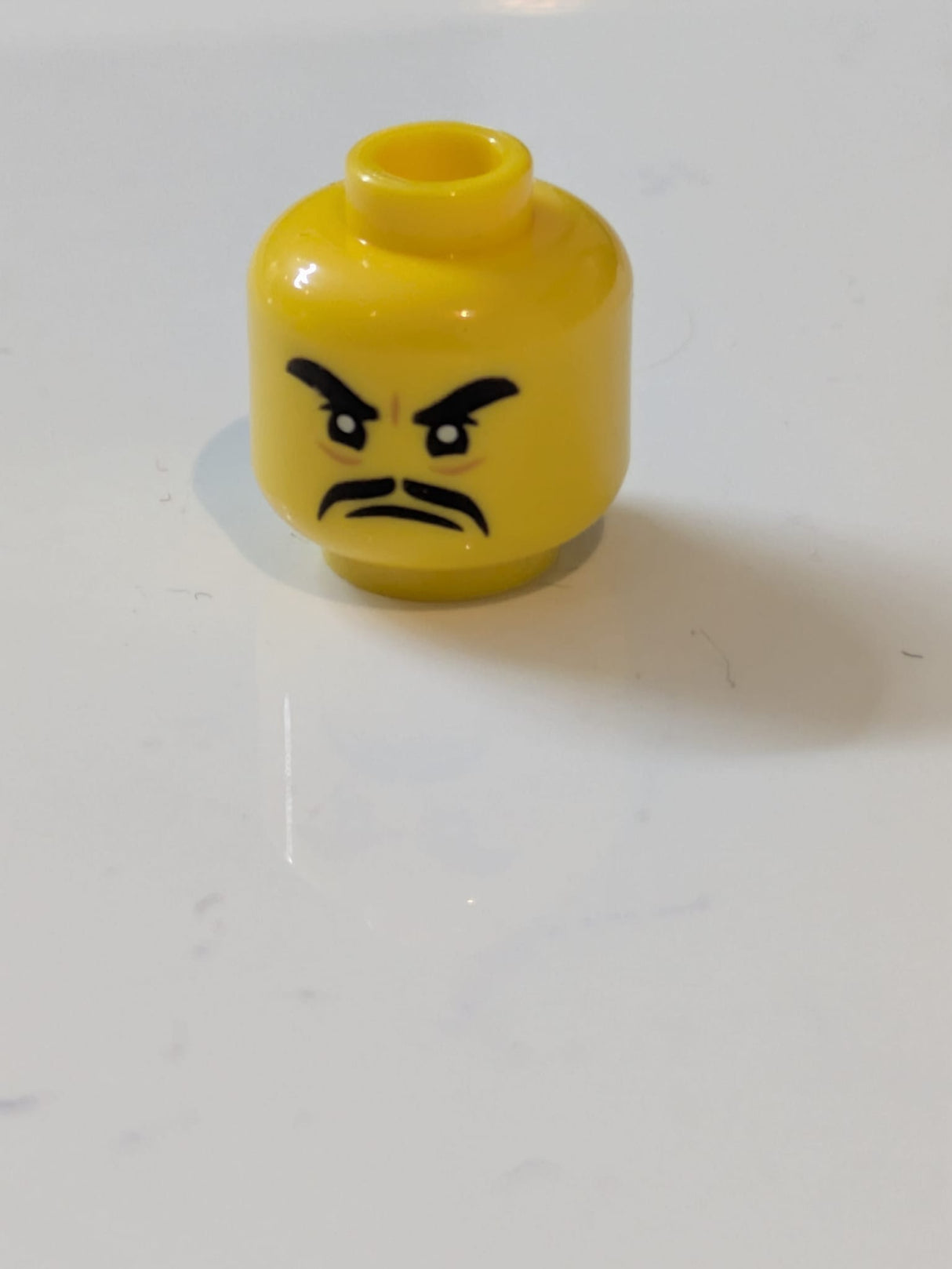 Minifigur, Kopf mit schwarzen, dicken Augenbrauen und Schnurrbart, wütender Gesichtsausdruck gelb