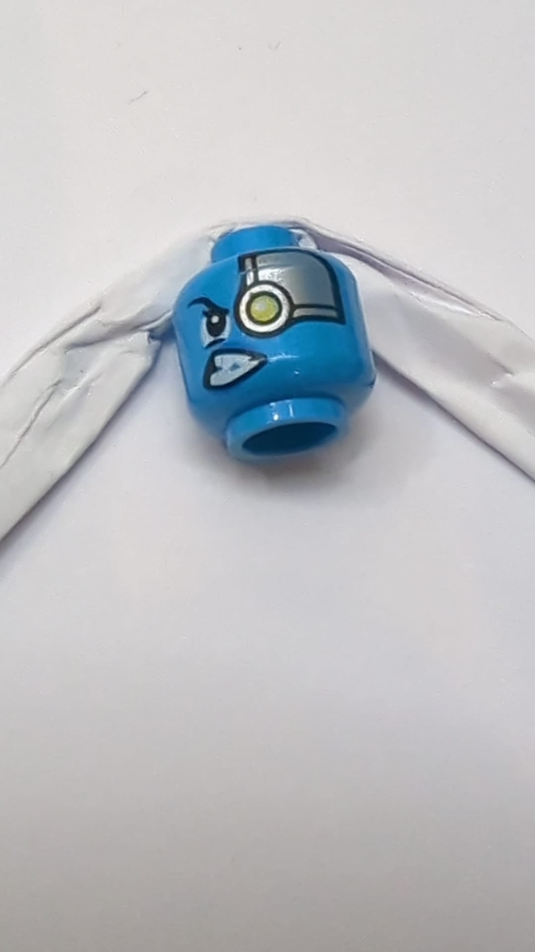 Minifigur, weiblicher Alienkopf mit silberner Kopfplatte und gelbem Roboterauge links, schiefem Gesichtsausdruck dunkelazur