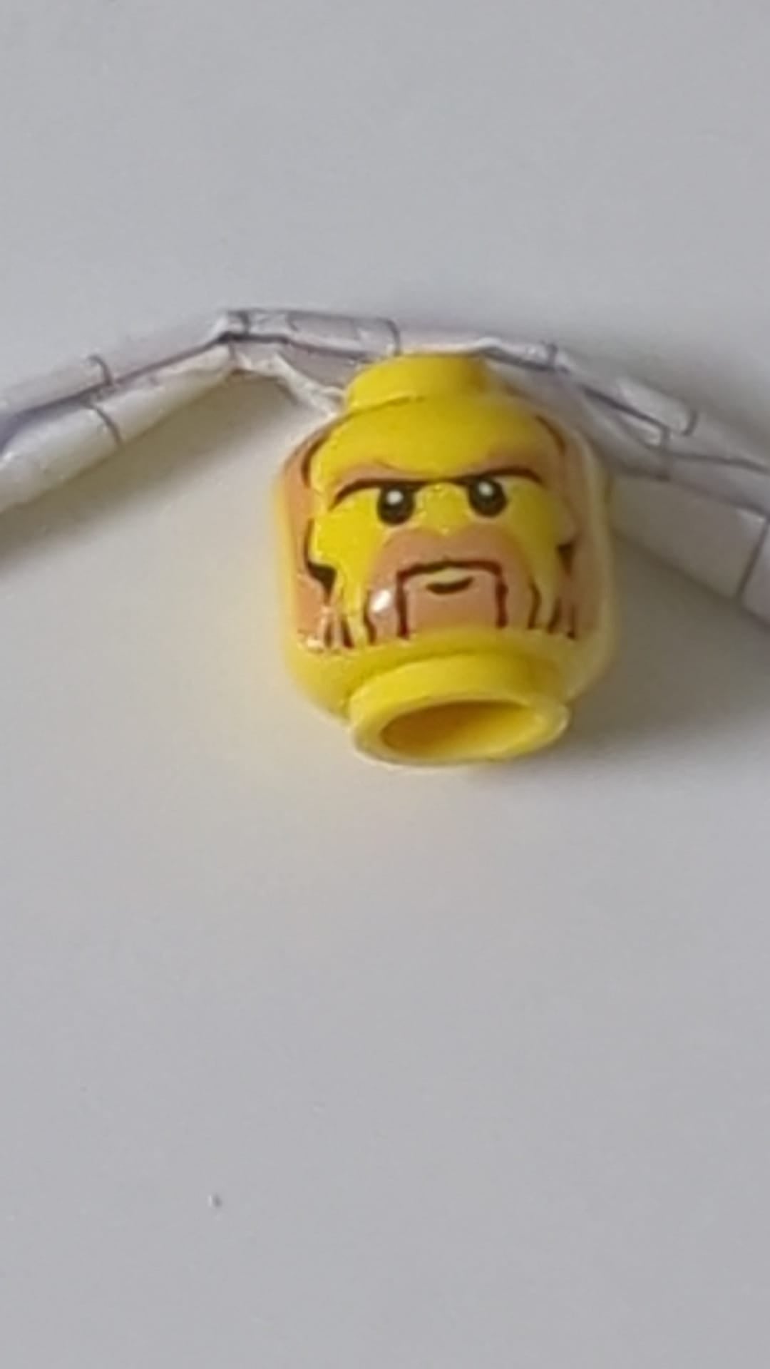 Minifigur, Kopf schwarz und nougatfarben, Bart, Koteletten, buschige Augenbrauen, weiße Pupillen, strenges Muster gelb