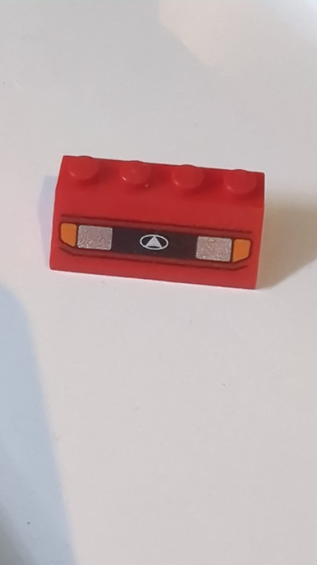 2x4 Dachstein 45° mit silbernen Autoscheinwerfern, orangefarbenen Blinkern und schwarzem Kühlergrill mit weißem Dreieck-im-Oval-Logo rot