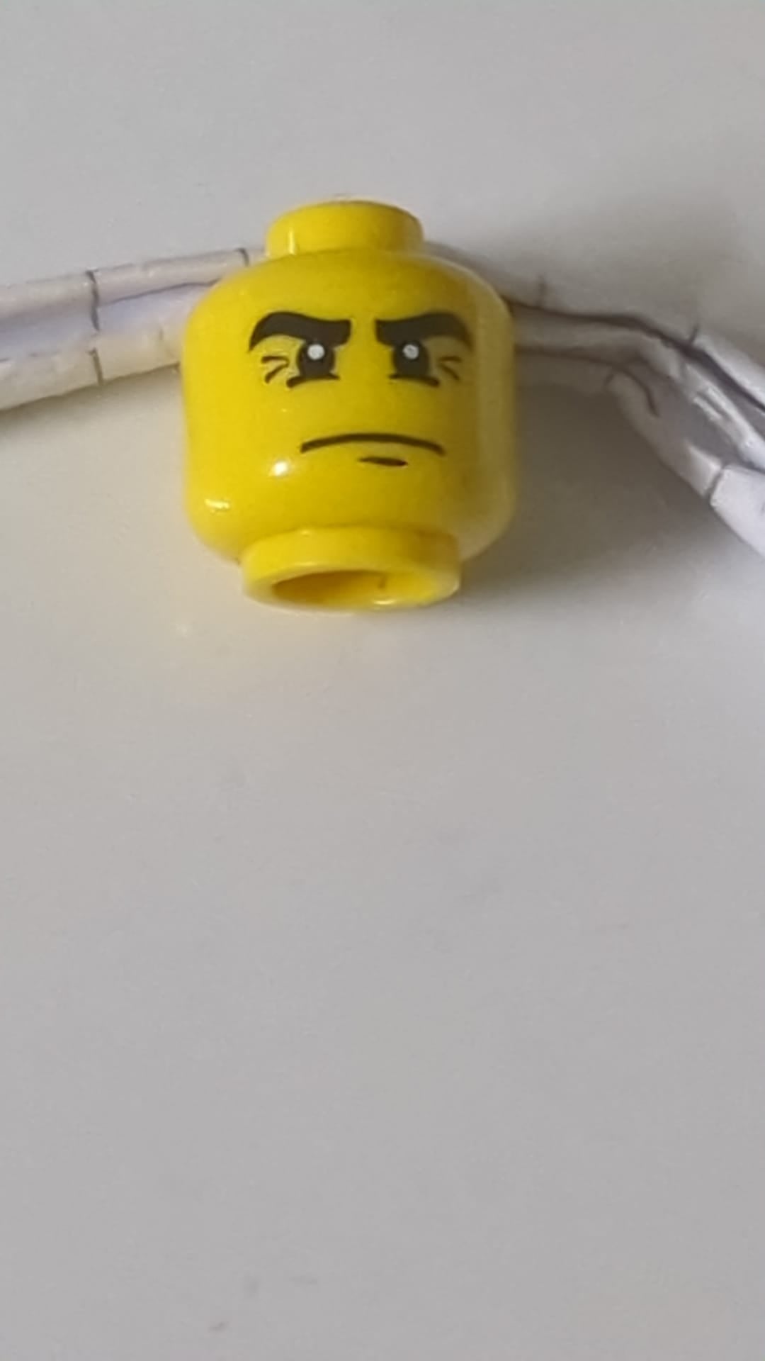 Minifigur, männlicher Kopf, schwarze Augenbrauen mit Krähenfüßen, Falten und weißen Pupillen. gelb