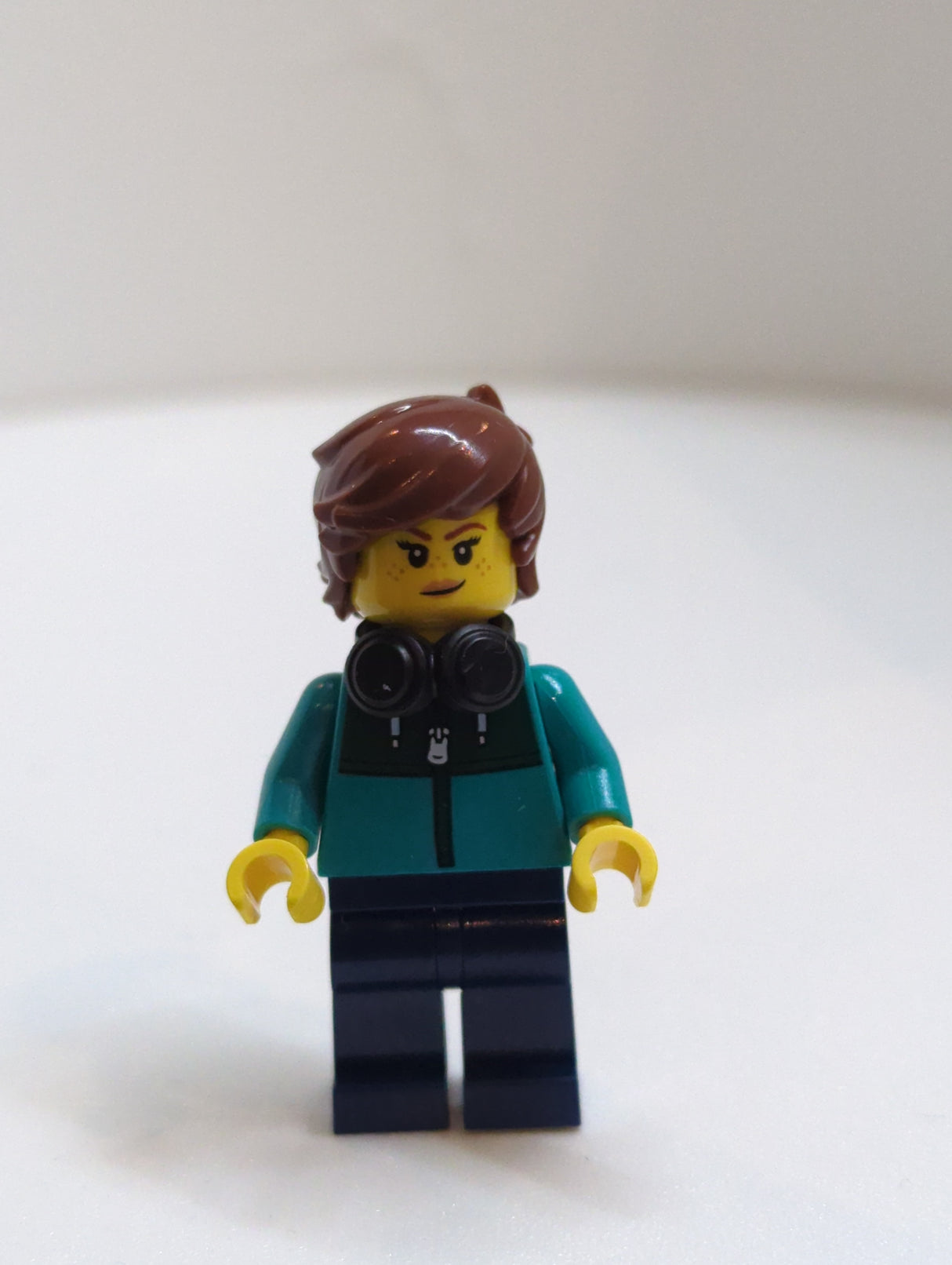 NEU Town Minifigur Tudor House Resident - Dunkeltürkisfarbene Jacke mit dunkelgrünem Panel, dunkelblaue Beine, rotbraunes zerzaustes Haar, schwarze Kopfhörer twn516