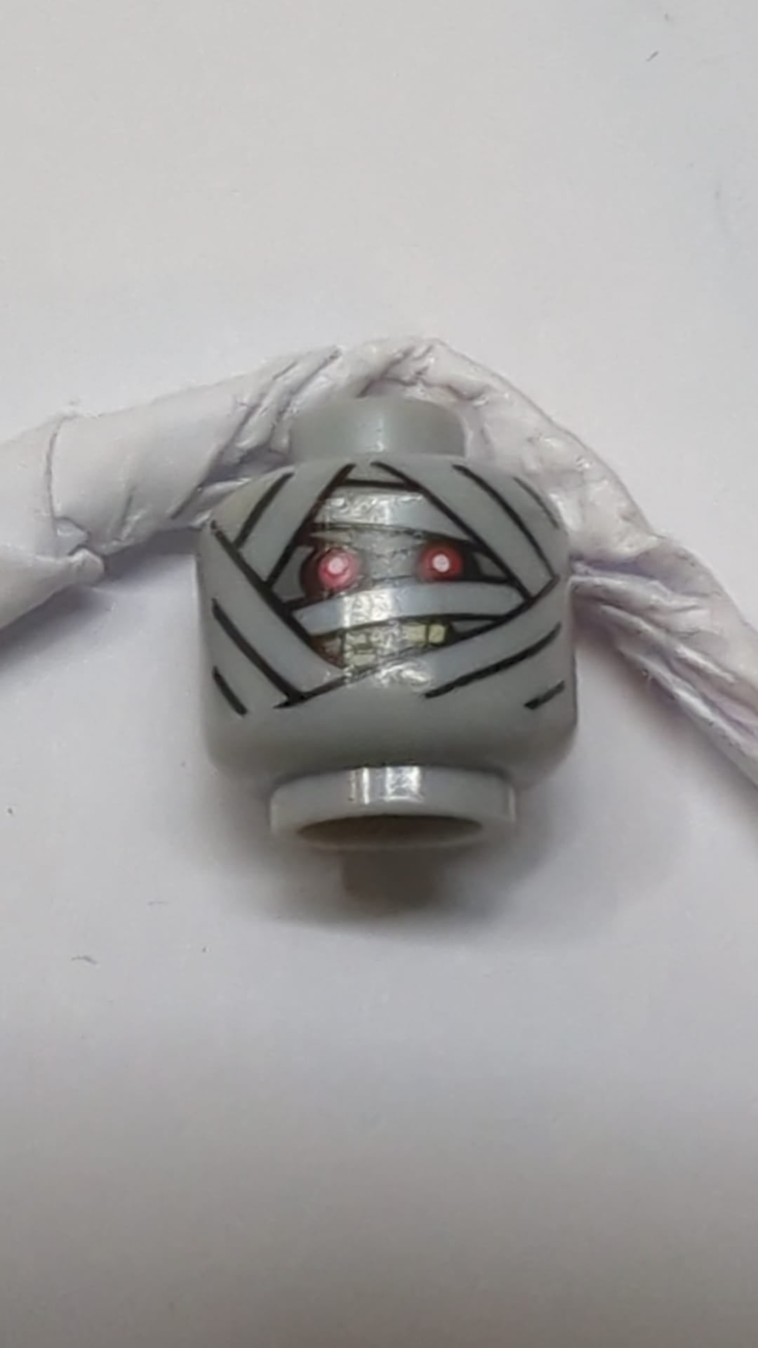 Minifigur, doppelseitiger Kopf einer Alien-Mumie mit dunkelblaugrauem Gesicht, Bandagen, roten Augen und wütend geöffnetem Mund mit gespreizten Zähnen / einzelnes Auge neuhellgrau