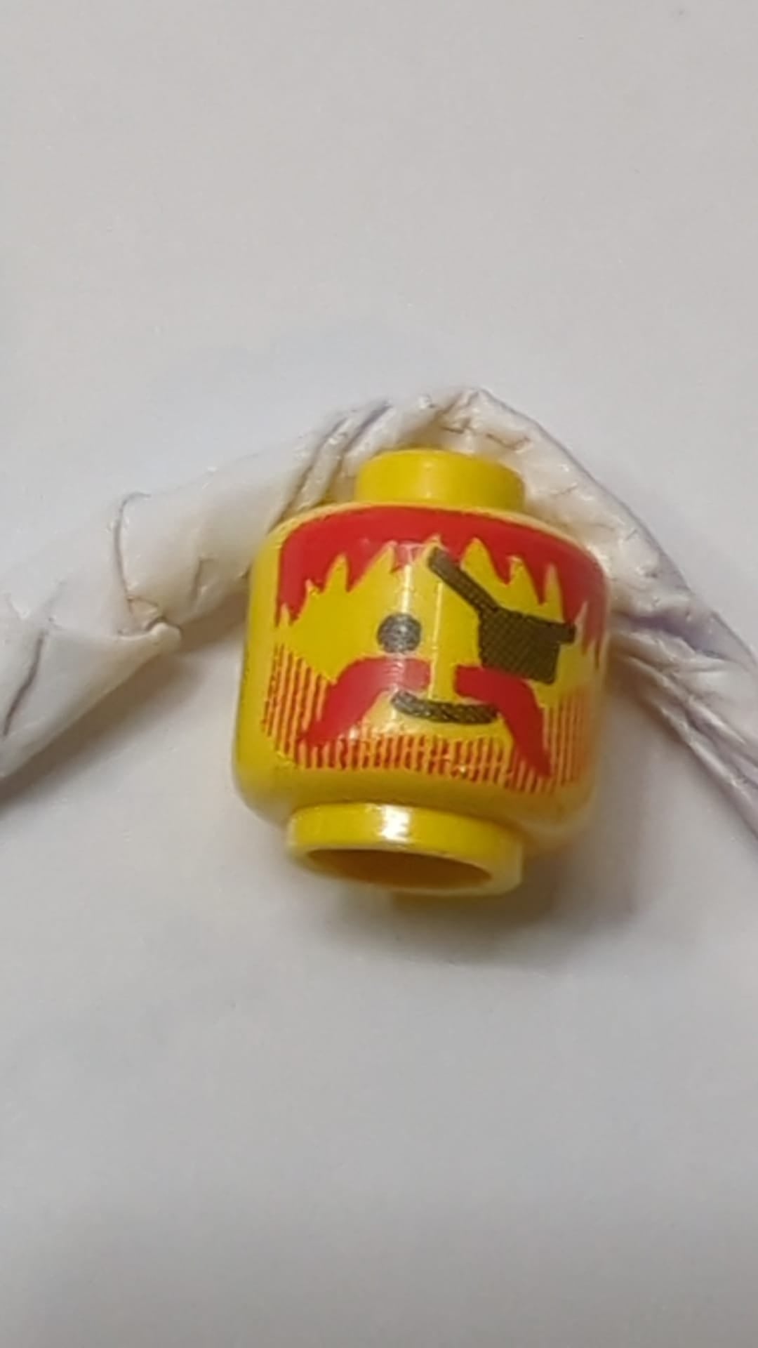 Minifigur, Standard-Kopf mit grinsendem Gesicht, dunkelrotem, wuscheligem Haar, Schnurrbart und Bart mit vertikalen Linien, schwarzes Augenklappenmuster gelb