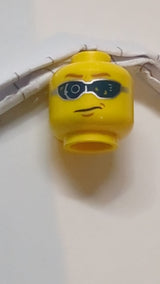 Minifigur, digitaler Kopf mit Brille, hellbraunen Augenbrauen und Grübchenmuster am Kinn gelb