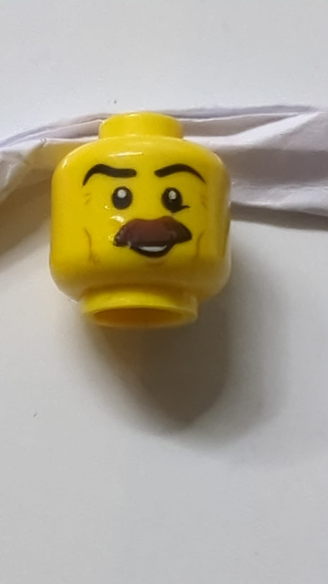 Minifigur, Kopf, brauner, buschiger Schnurrbart, schwarze Augenbrauen, Wangenfalten, Lächeln, weiße Pupillenmuster gelb