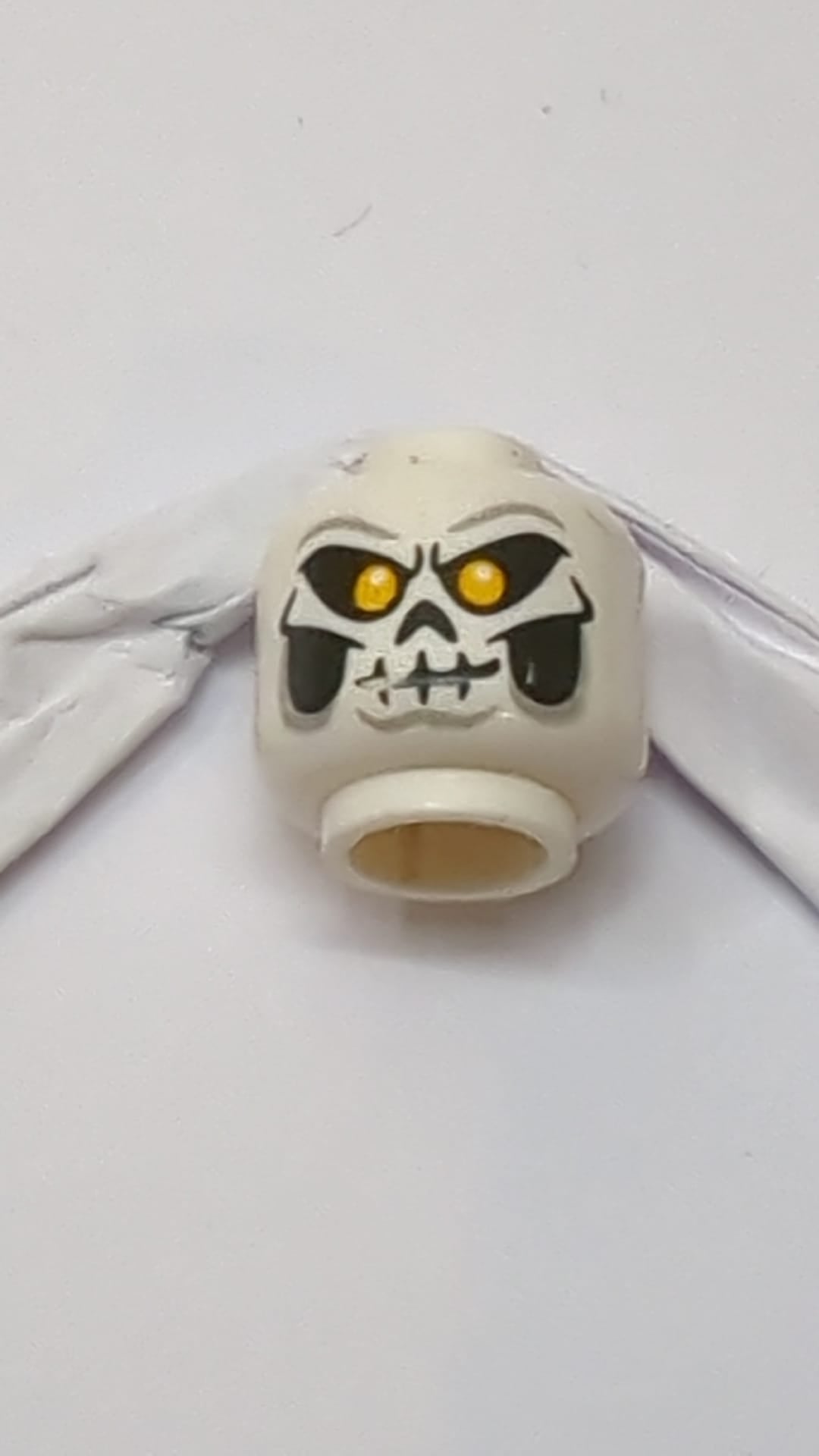Minifigur, doppelseitige Totenkopfmaske mit leuchtend orangefarbenen Augen, Skelettmund mit Lächeln/Stirnrunzeln weiß