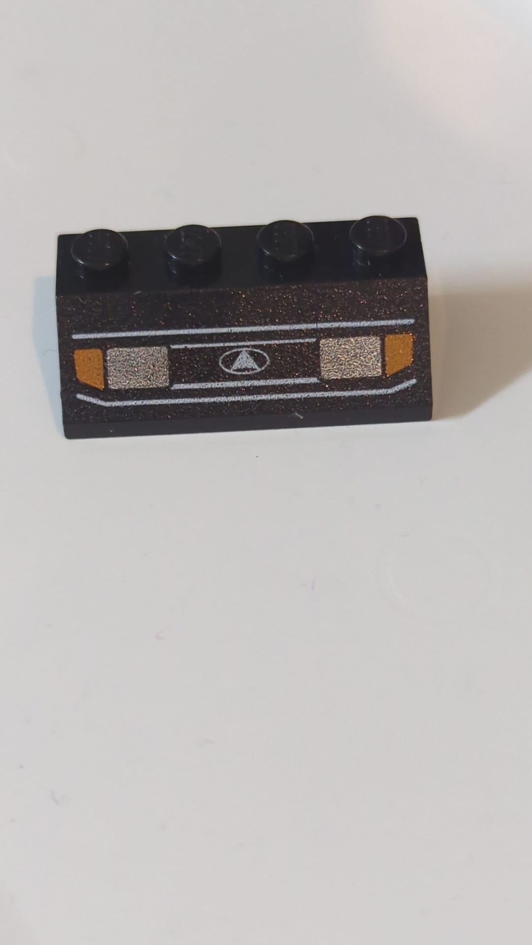 2x4 Dachstein 45° mit silbernen Autoscheinwerfern, orangefarbenen Blinkern und Kühlergrill mit weißem Dreieck im ovalen Logo-Muster schwarz
