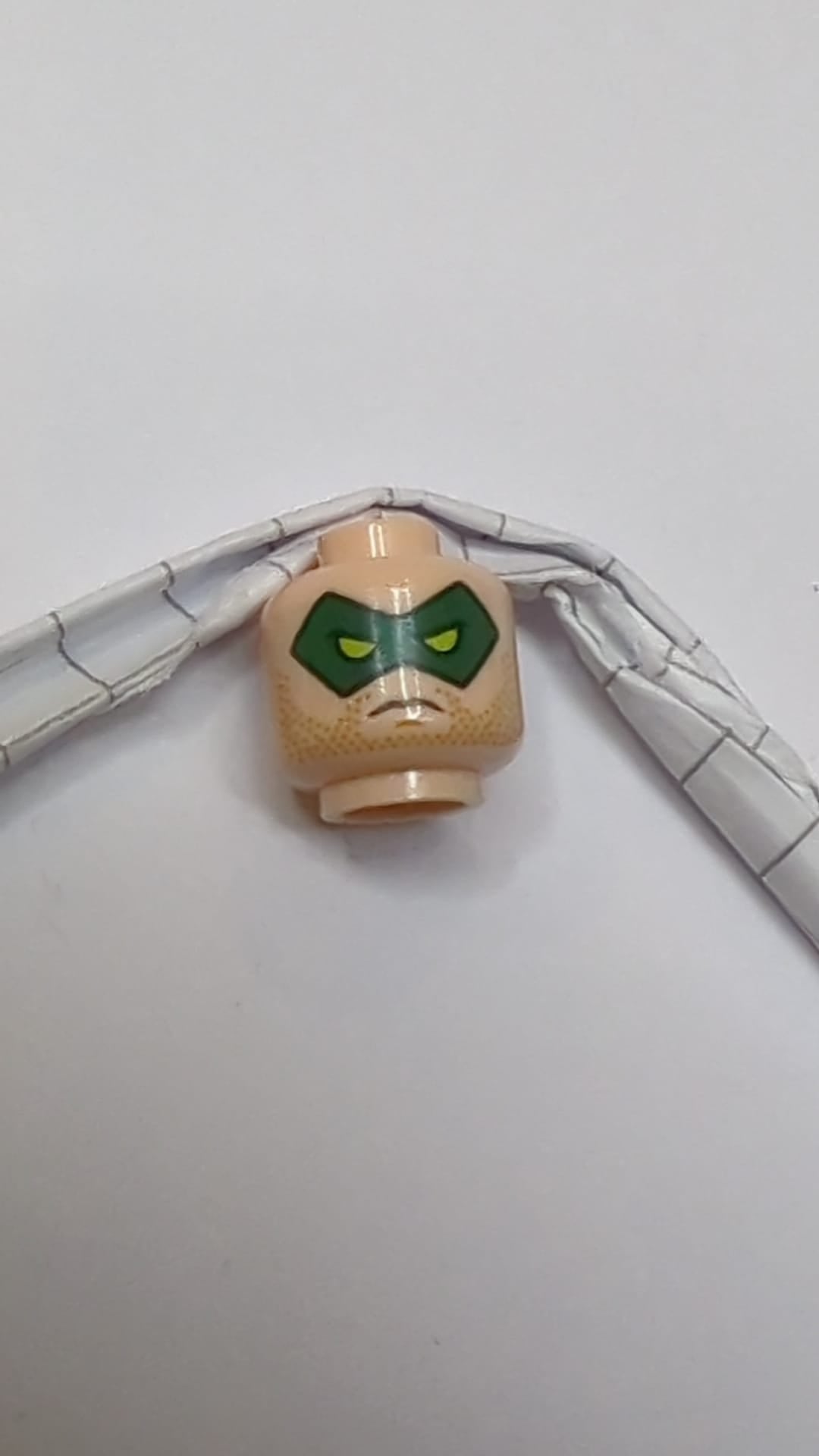 Minifigur, Kopf, doppelseitige grüne Augenmaske mit Augenlöchern, Grinsen-/Stirnrunzelmuster hellnougat (fleischfarben)