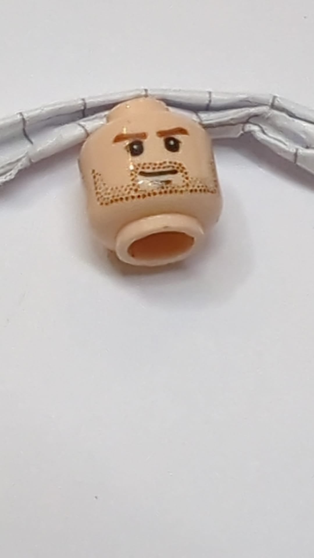 Minifigur, männlicher Kopf, rötlich-braune Augenbrauen, mittellanger, nougatfarbener Bartstoppeln, Grübchen am Kinn und geschlossener Mund mit schiefem Grinsen hellnougat (fleischfarben)